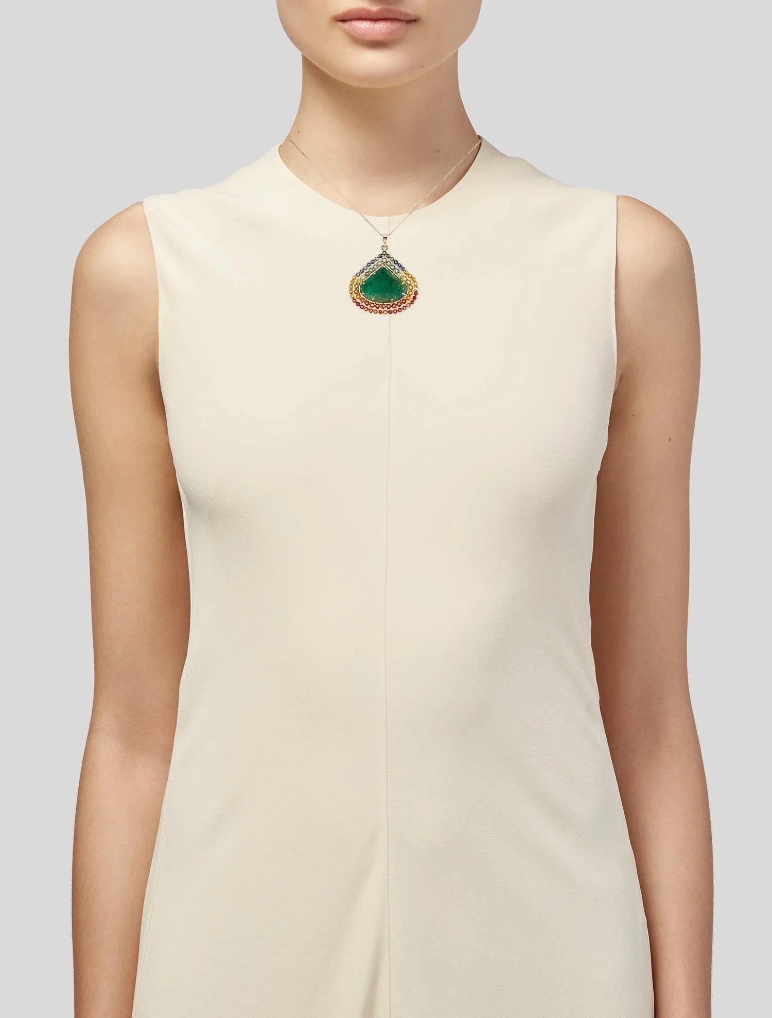 This striking 14K Yellow Gold Pendant Necklace features a captivating combination of emerald and sapphire gemstones, creating a vivid and eye-catching statement piece. The necklace showcases a beautifully carved triangular emerald, complemented by
