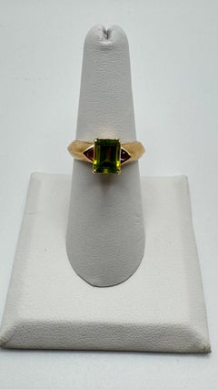 Anillo de oro amarillo de 14 quilates con peridoto talla esmeralda y acento de rubí, 3,50 ct de peso total