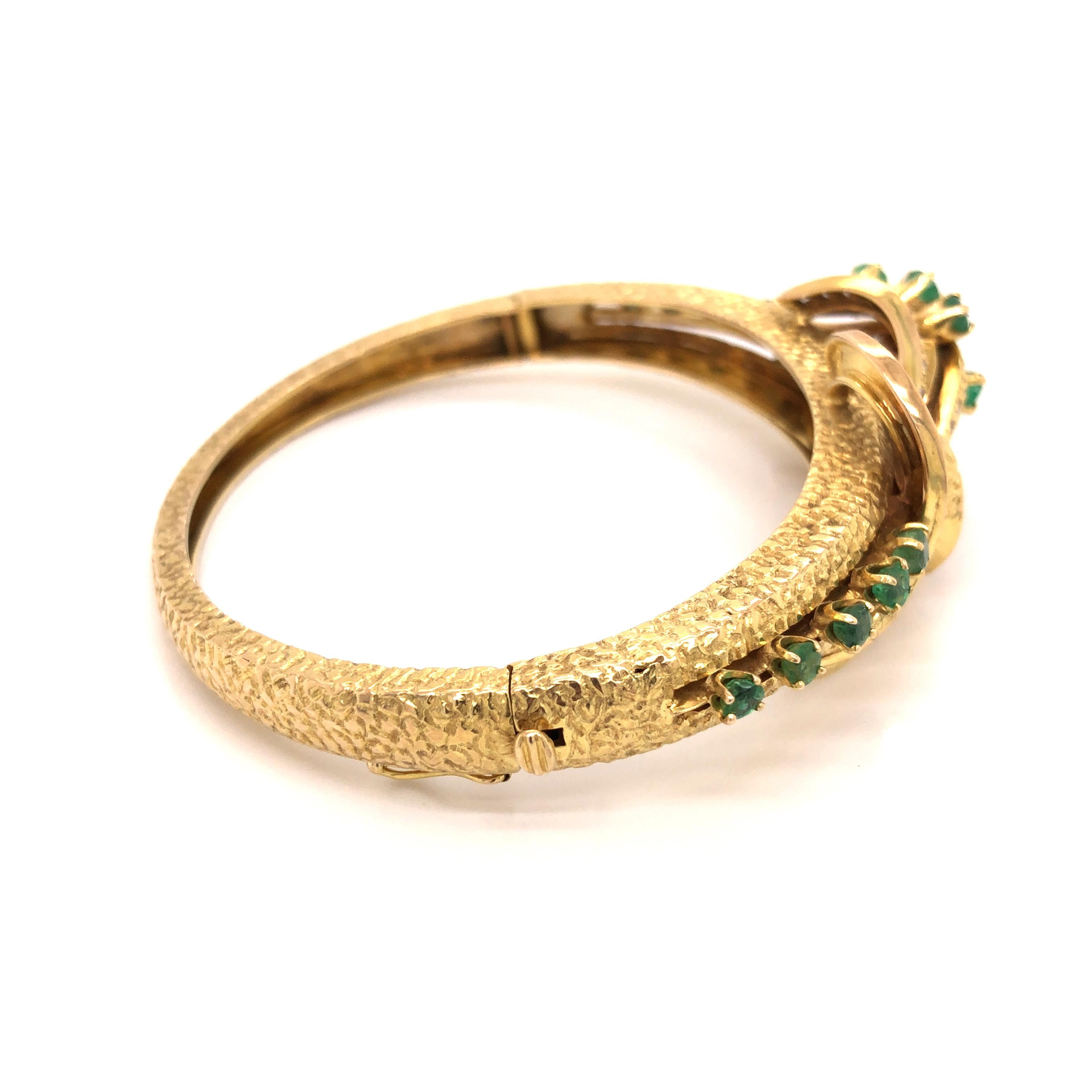 14K yellow gold hinged bangle containing an elaborate chased coiling ribbon and raised swirls set with 16 round emeralds weighing a total of approximately 1.05 carats and 30 round-cut diamonds weighing a total of approximately .35 carat,H-I color,SI