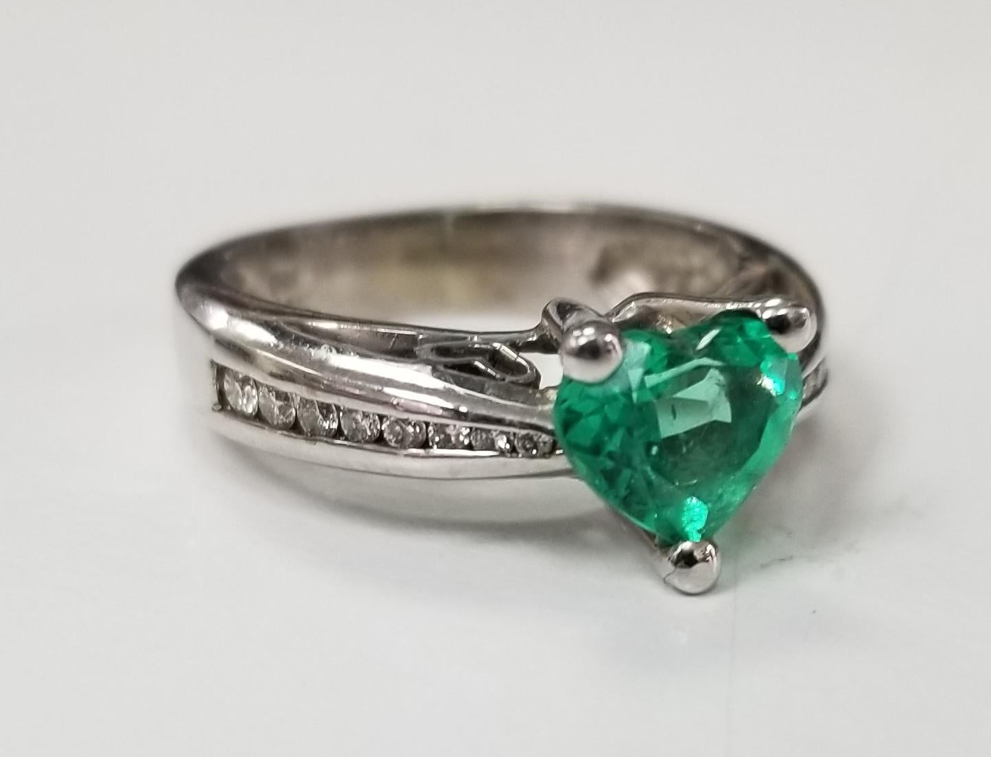 14k yellow gold Emerald and diamond ring, containing 1 heart shape cut emerald of gem quality  weighing 1.03cts. and 16 round full cut diamonds weighing .20pts.  This ring is a size 5 but we will size to fit for free.