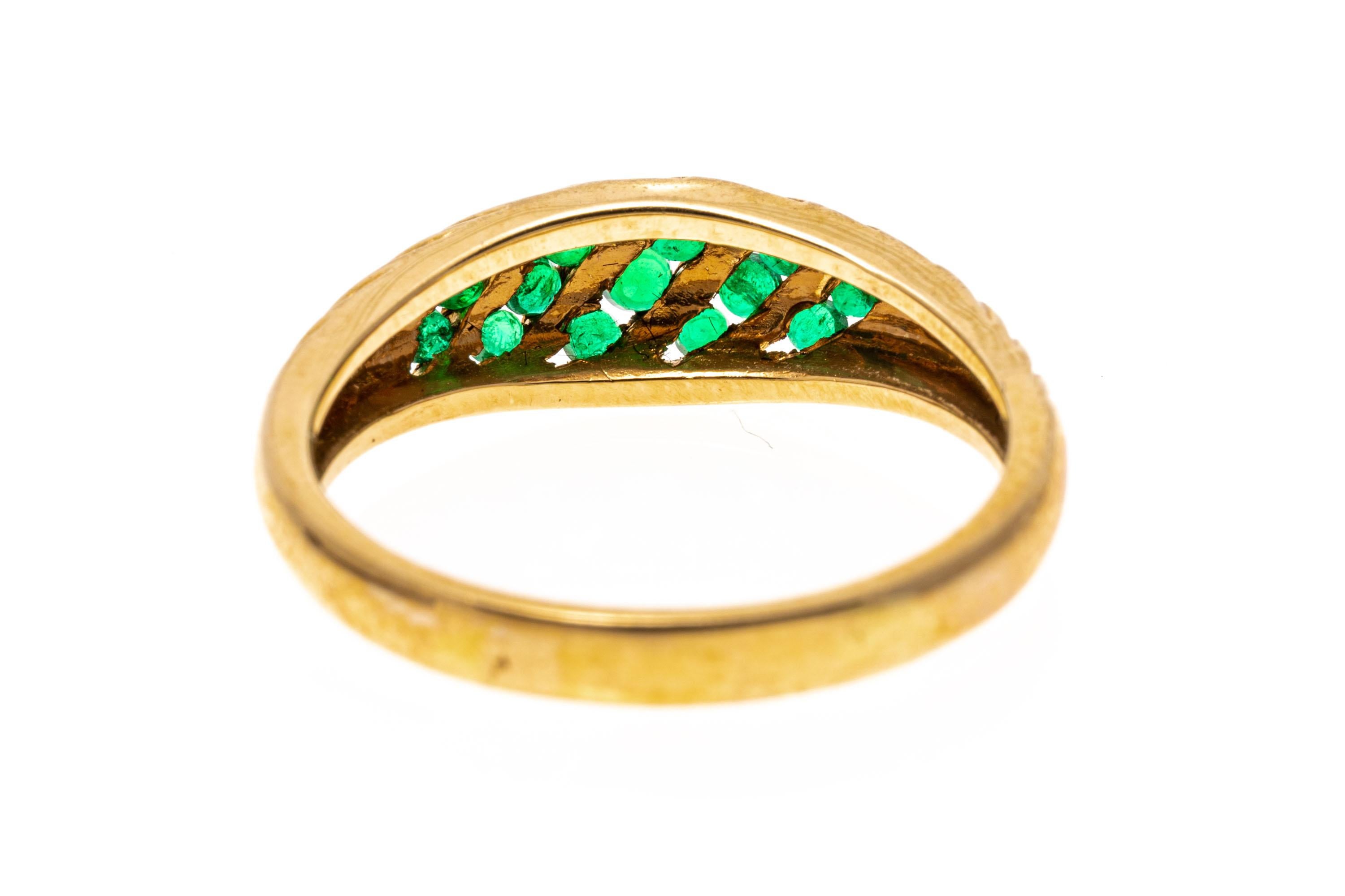 14k yellow gold ring. This pretty ring is a ribbed, domed style, with an angled, channel set center cluster of round faceted, medium green color emeralds, approximately 0.40 TCW.
Marks: 14k
Dimensions: 1/2