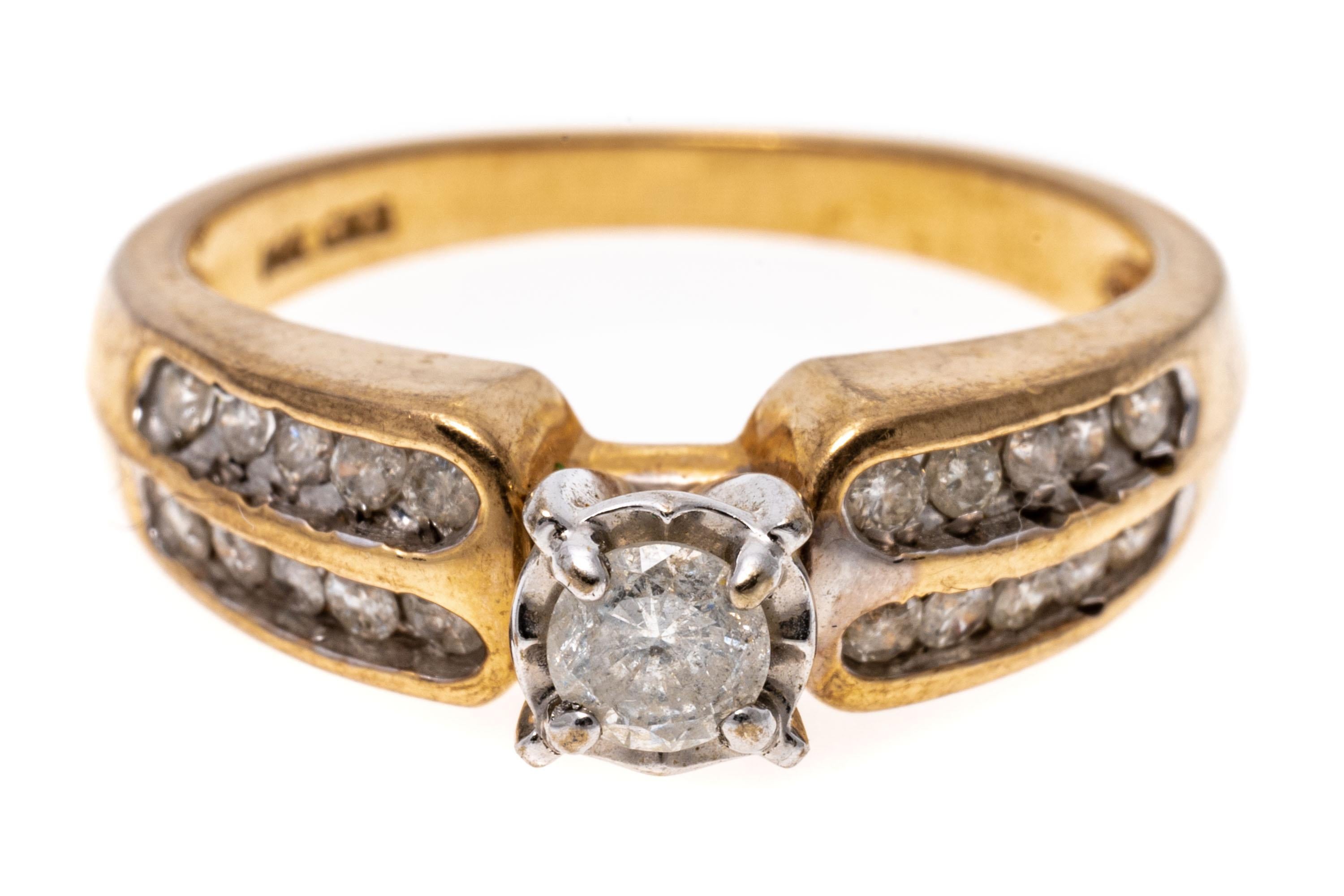 14k yellow gold ring. This classic engagement ring has a round brilliant cut center, approximately 0.17 CTS and set into an illusion style top, and is flanked by two rows of channel set, round faceted diamonds, approximately 0.20 TCW. The stones are