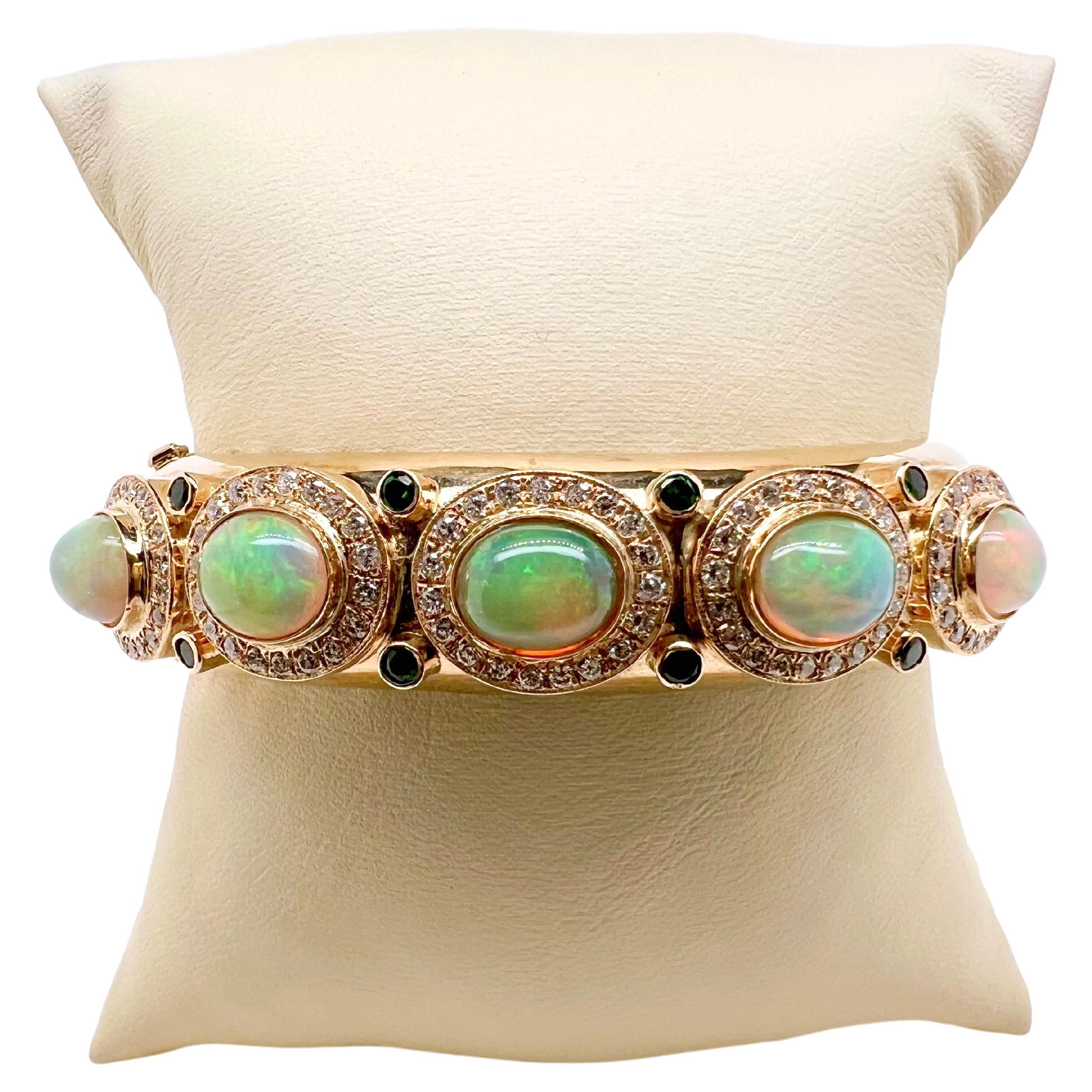This stunning bangle is handmade with meticulous details.  TheEthiopian opals are bezel set with round brilliant diamonds and stunning Tsavorite green garnets surrounding it.  The vibrant opal stands out agains the yellow gold and the bangle has an