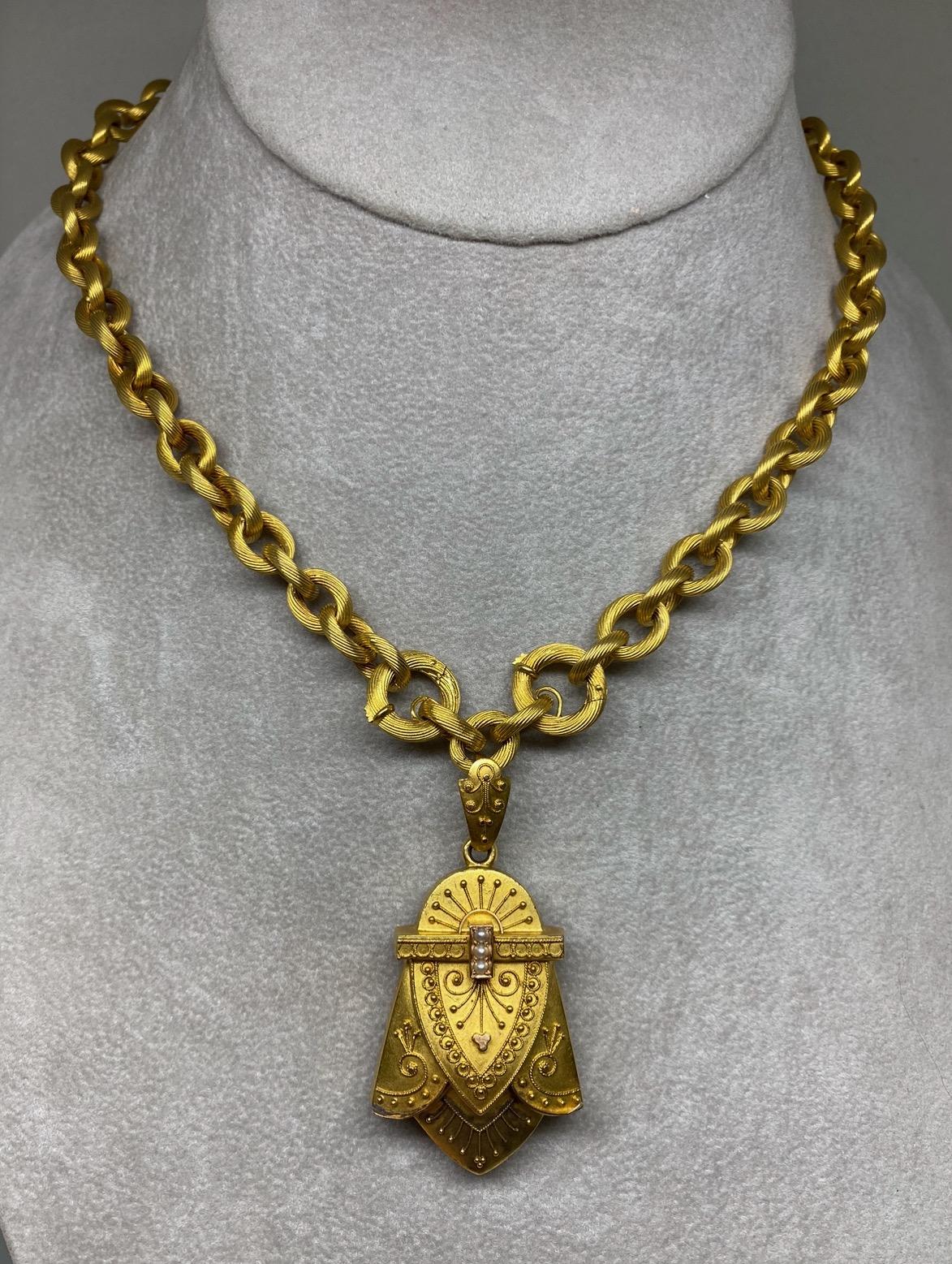 Dating back to the 1870s, this fabulous Victorian locket necklace, is artfully ornamented in consummate Etruscan Revival style.  The locket suspends from a very fine 20 inch chain made up of gold ribbed circle links. A rare find to have both the