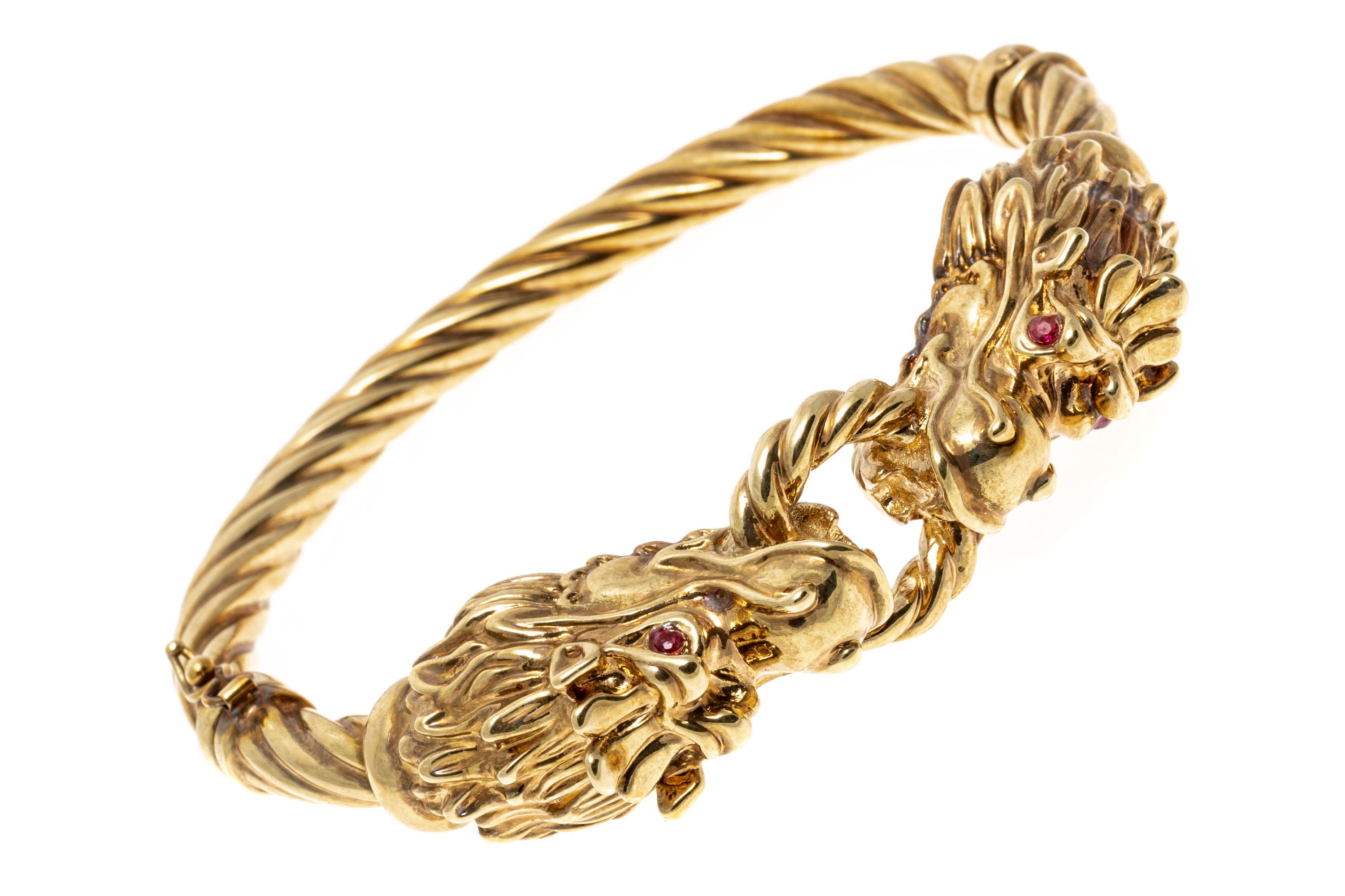 14k Yellow Gold Facing Dragons Hinged Twisted Bangle Bracelet
This striking twisted hinged bangle bracelet features an impactful center of two facing figural dragon's heads, holding a twisted center ring of yellow gold in their mouths between them.