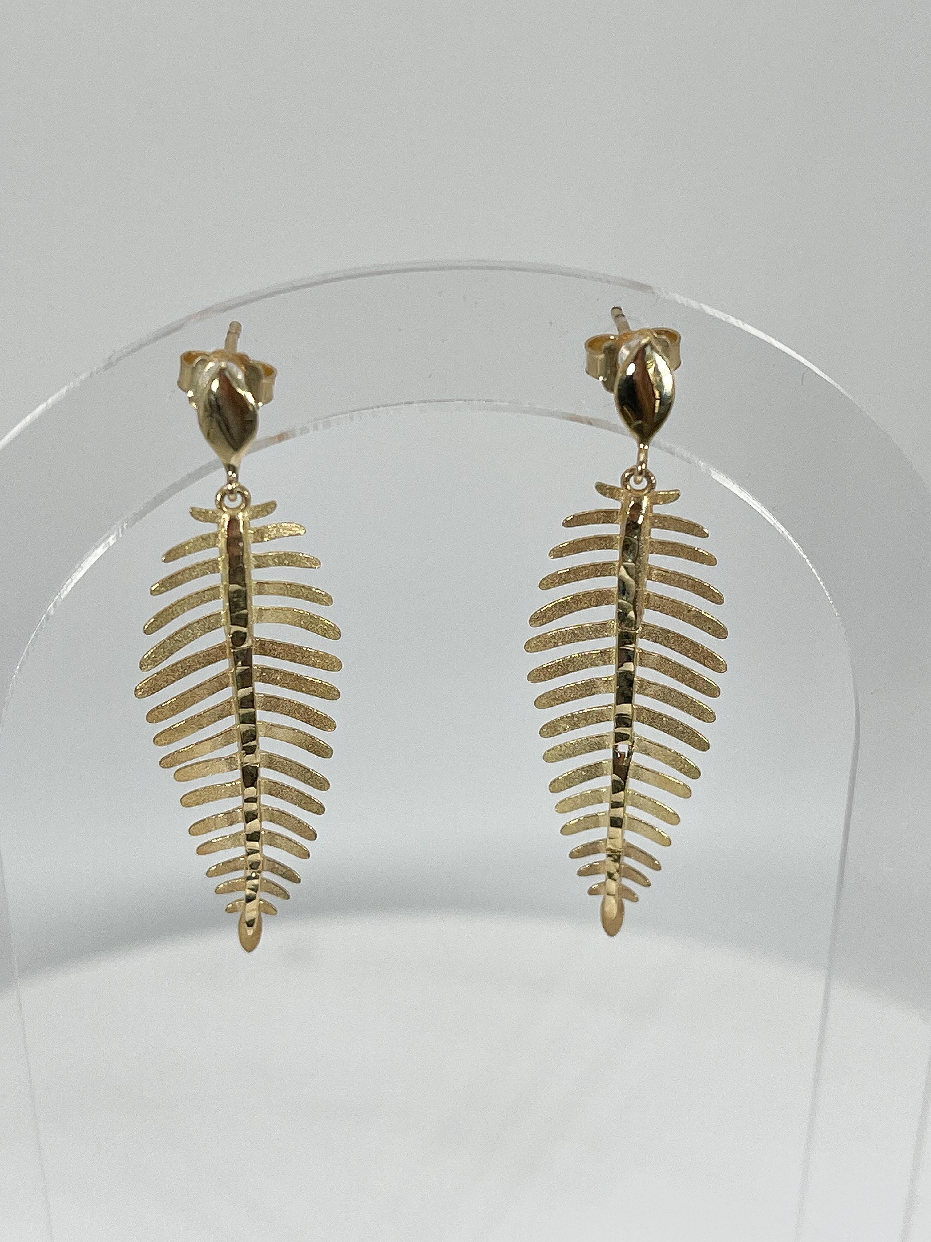 14k yellow gold feather dangle earrings. These earrings measure to be 50mm x 14mm, they have a friction back for wearing, and they have a total weight of 3.5 grams.