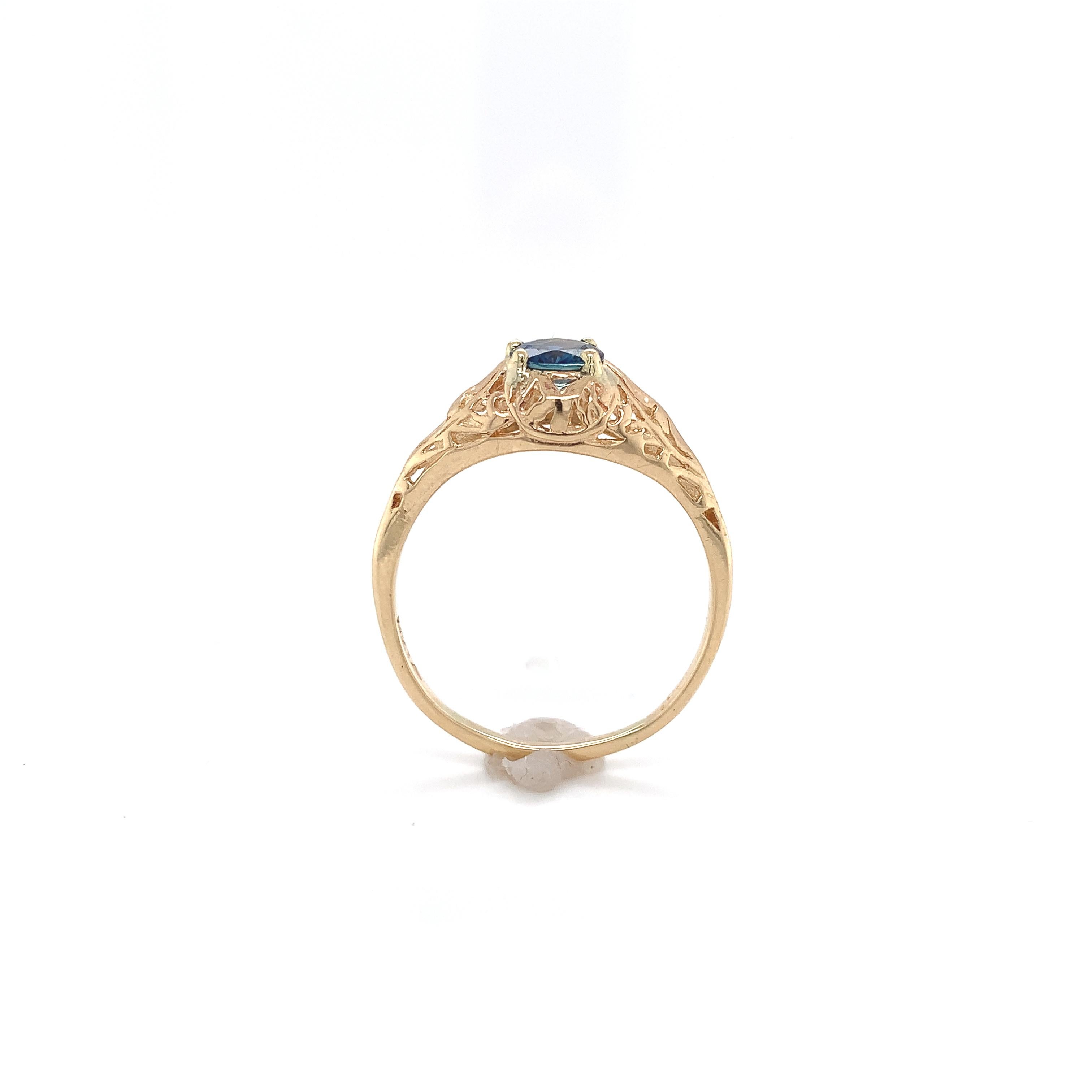 14K yellow gold filigree ring featuring a genuine blue sapphire weighing .63cts. The round sapphire measures about 5.3mm. The ring fits a size 8.75 finger, weighs 1.42 dwt. and is a newer piece made in the Art Deco style.