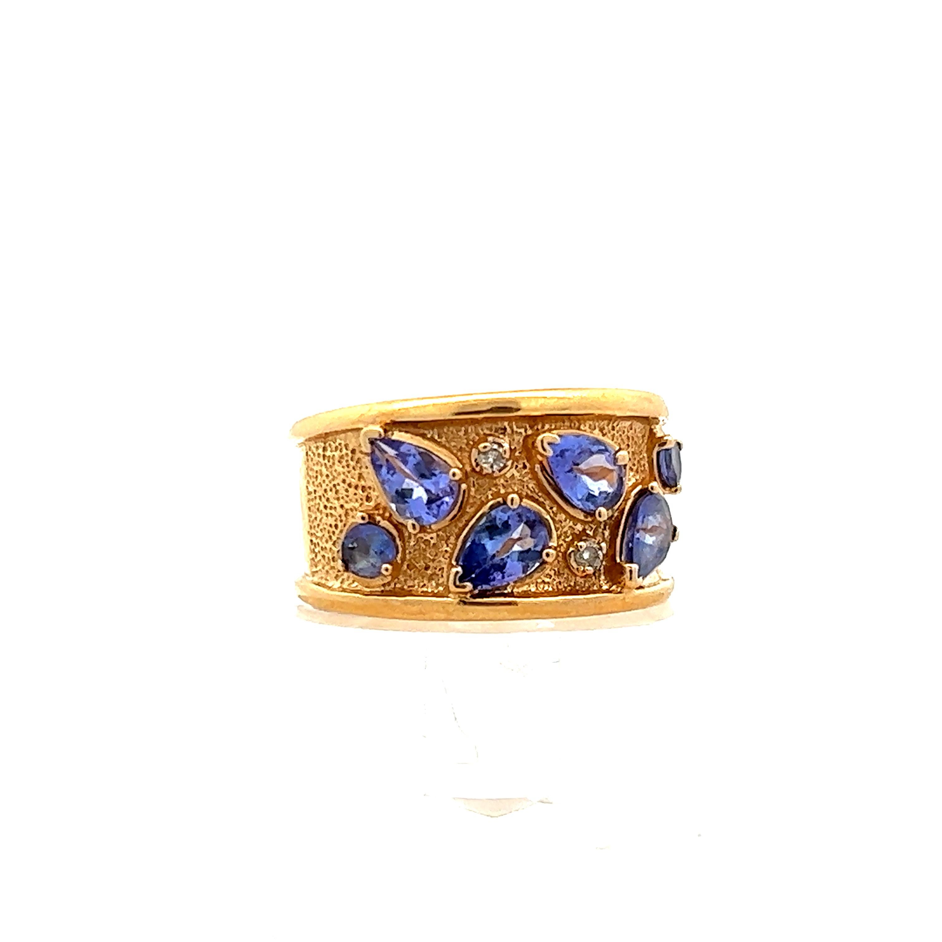 This lovely 14k yellow gold ring/cigar band features  pear and round shaped tanzanite as well as diamond. The combination of the 14k yellow gold and lovely tanzanite is timeless and elegant. The color blend so beautifully and makes for an accessory