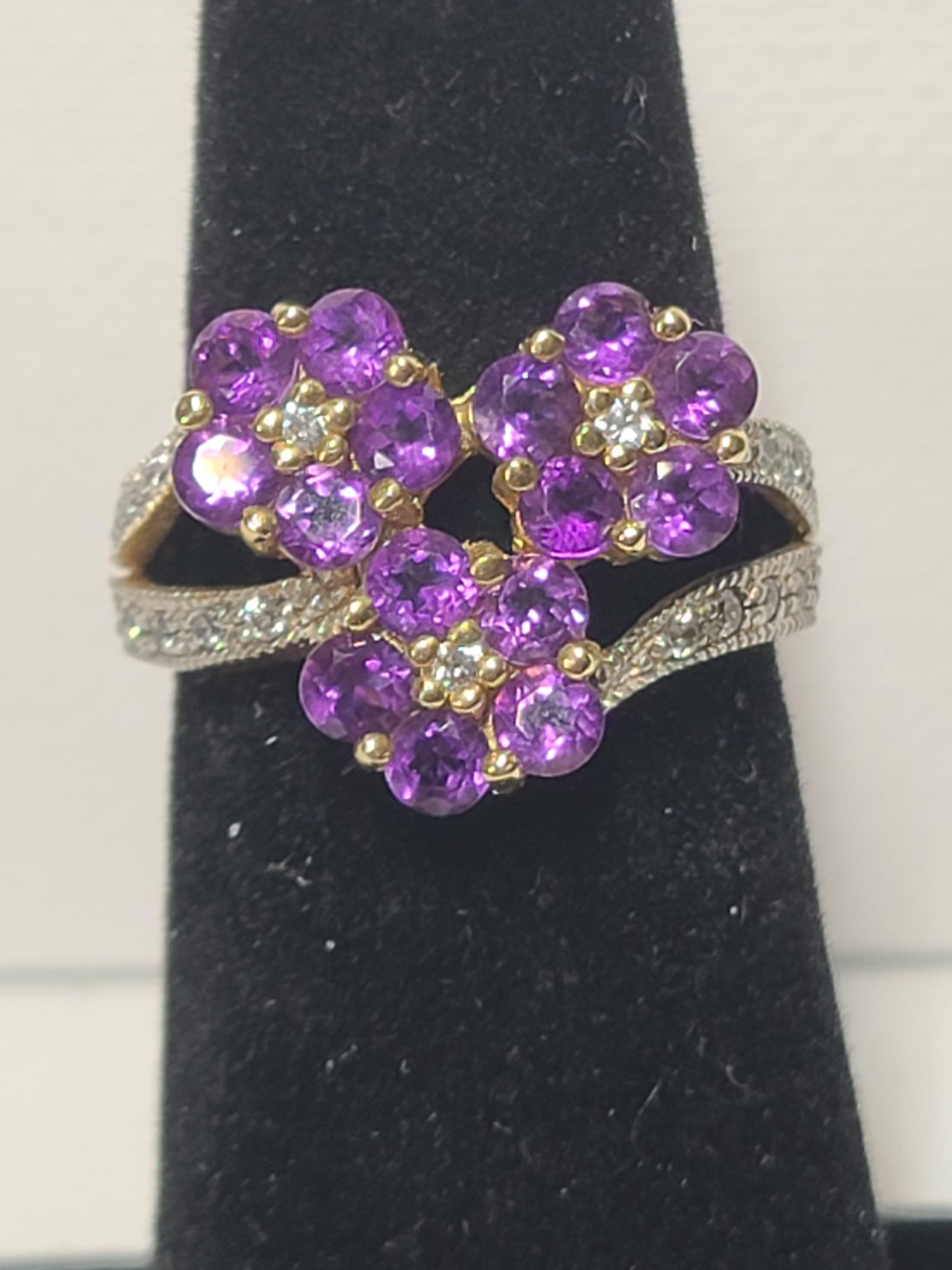 This fashionable ring features 15 small round cut amethysts with a diamond center made to look like 3 beautiful purple flowers, the band also features several accent diamonds set in 14K yellow gold.
The ring weighs 4.4 grams total.
The ring size is
