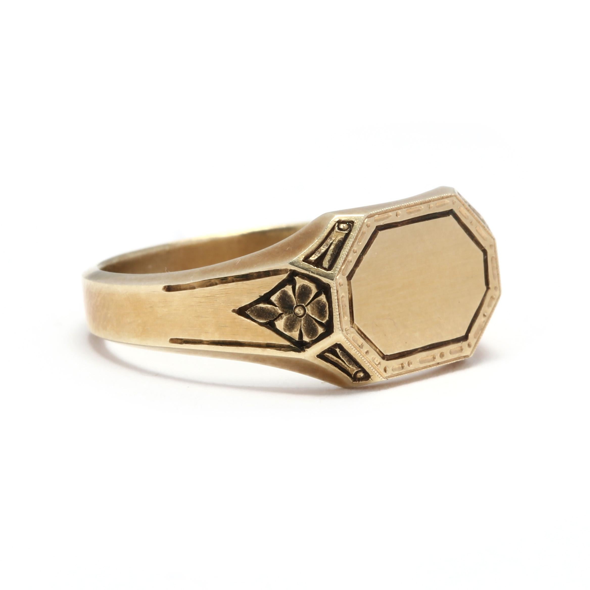 A 14 karat yellow gold floral signet ring. This ring features an elongated octagonal blank space waiting to be engraved with your initials, surrounded by a thin line border, with engraved detailing in a floral pattern and with a tapered shank.

Ring