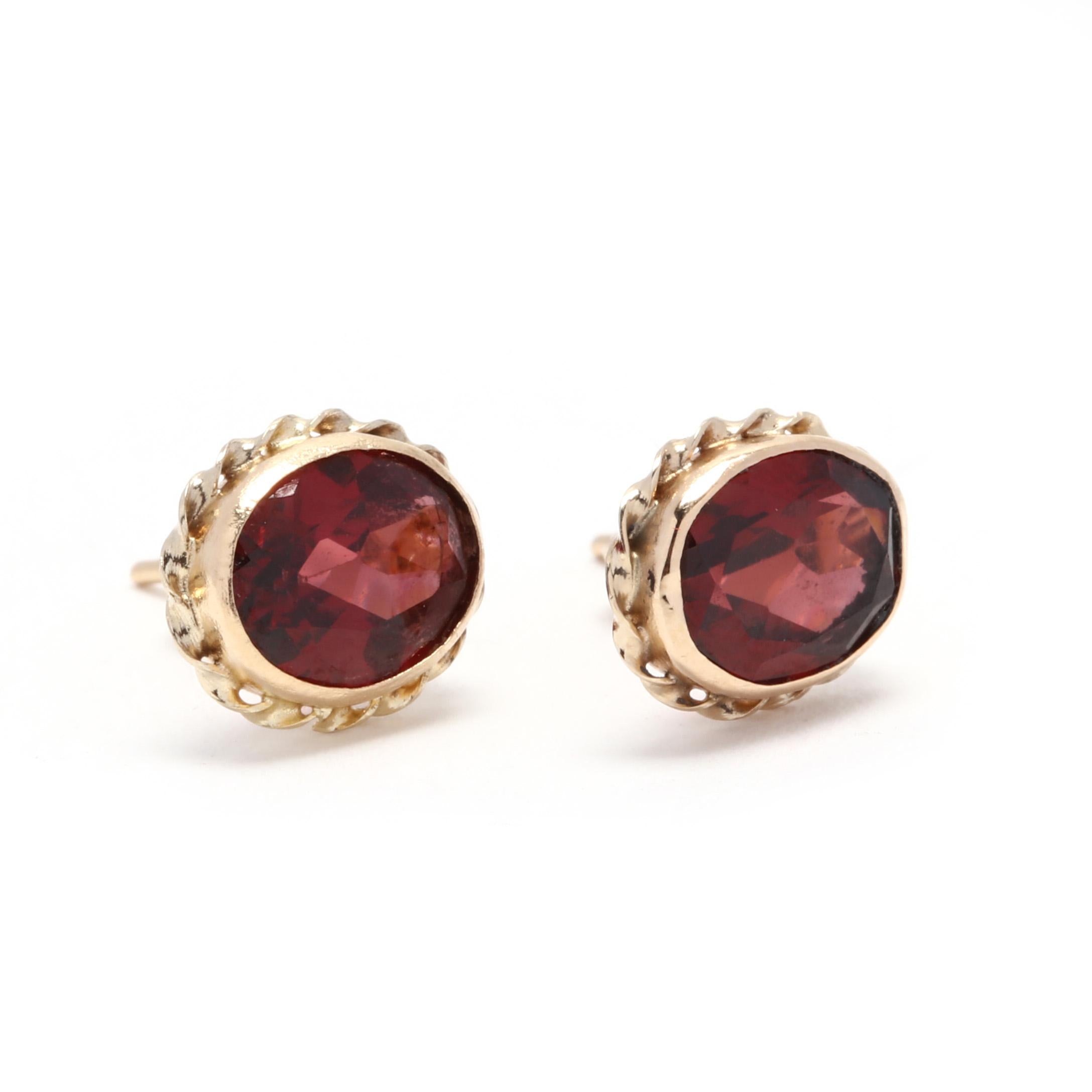 A pair of 14 karat yellow gold and garnet rope stud earrings. These earrings feature bezel, oval cut garnet stud surrounded by a twisted rope design and with push back closures.

Stones:
- garnet
- oval cut, 2 stones
- 7.5 x 5.5 mm
- approximately 2