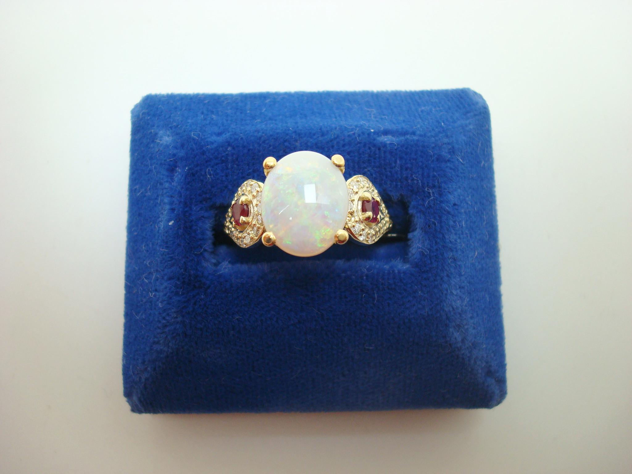 14k Yellow Gold Genuine Natural Opal Ruby and Diamond Ring (#J2650)

14k yellow gold opal, ruby, and diamond ring featuring a large oval opal weighing 2.05 carats. The opal measures about 11mm x 9mm. The opal has flashes of green, blue, and pink