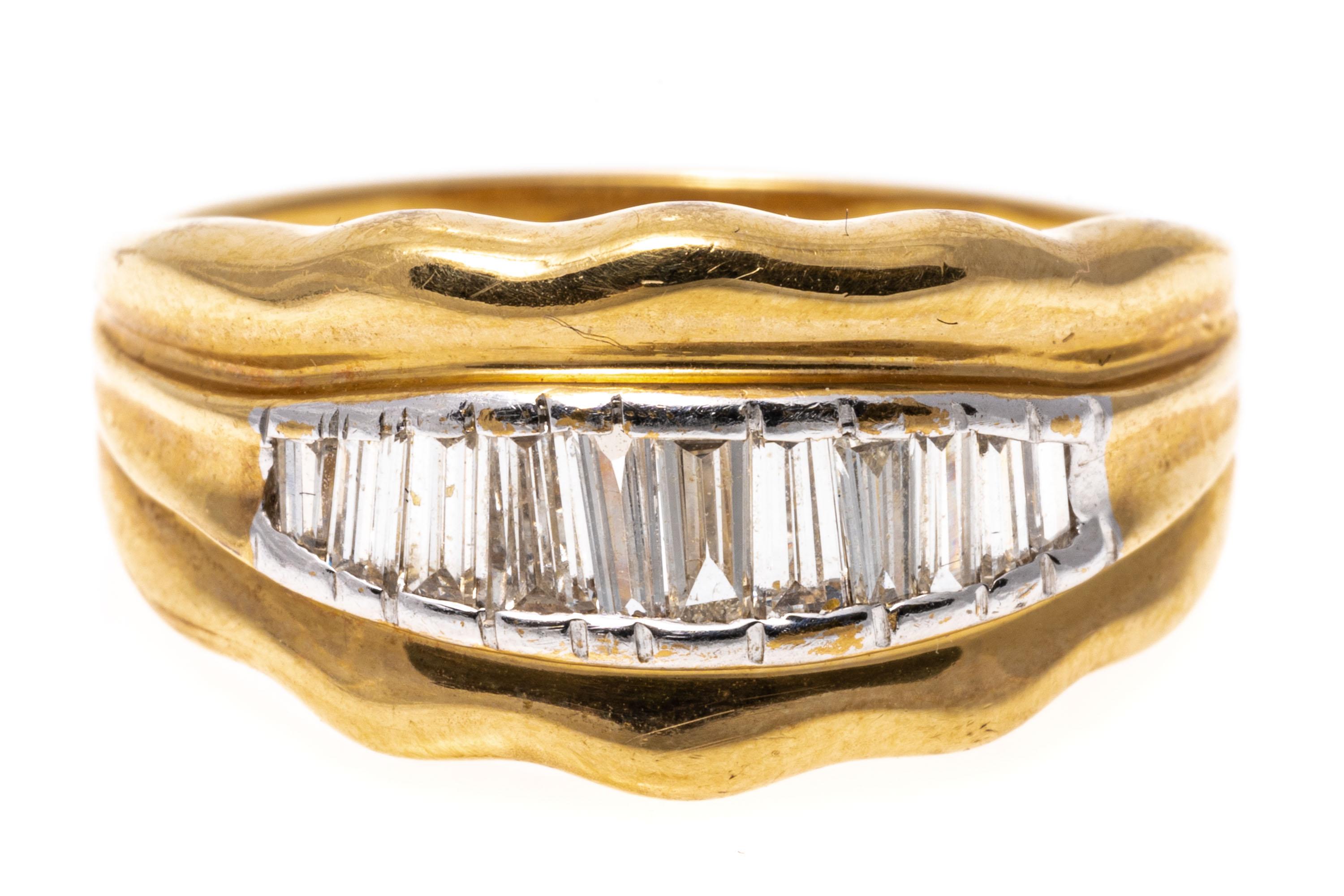 14k yellow gold ring. This interesting ring features a center row of graduated, baguette cut diamonds, channel set, approximately 0.31 TCW and framed by a tapered gold frame, finished with a scalloped edge.
Marks: 14k
Dimensions: 9/16
