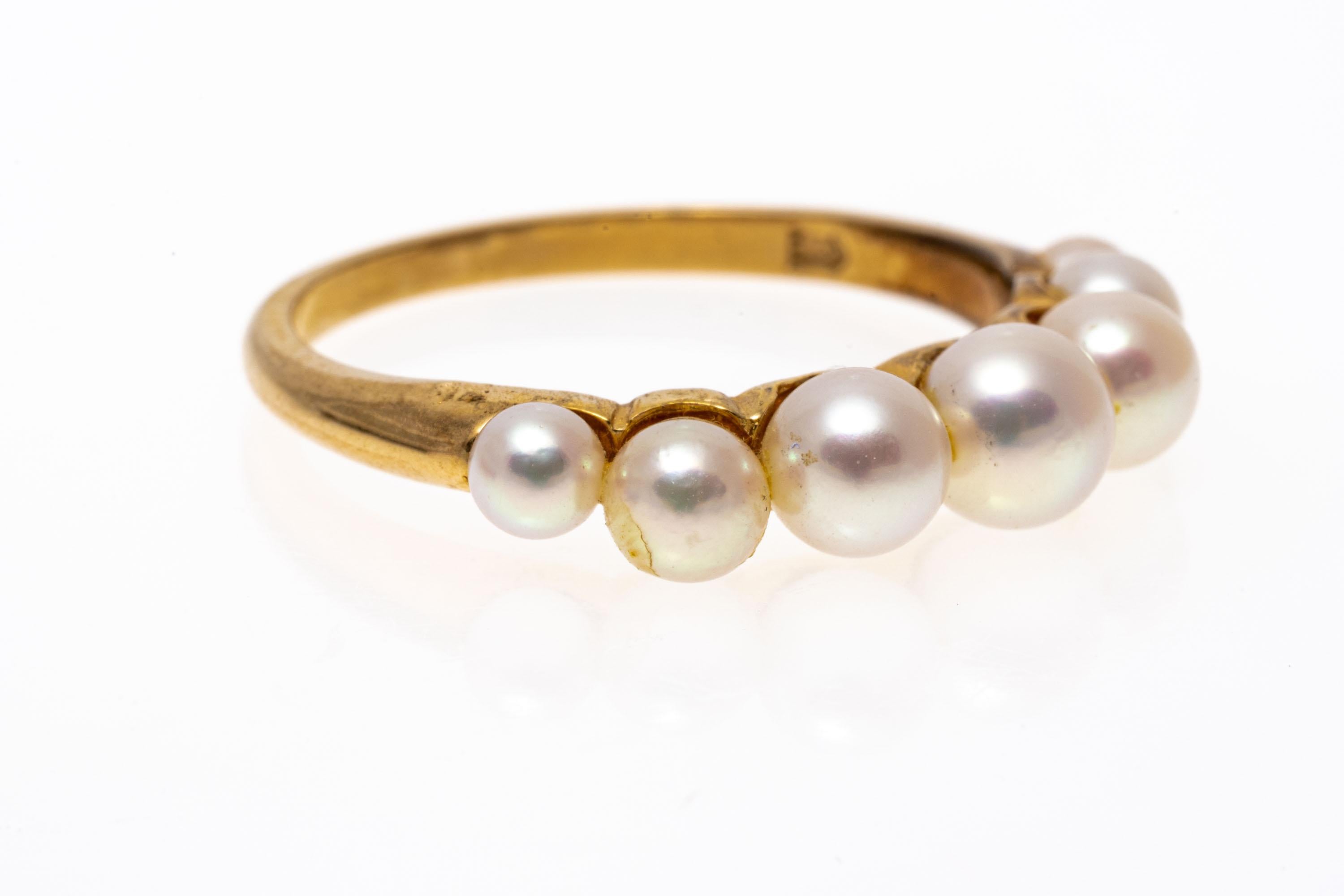 14K yellow gold ring. This pretty ring is a simple band of graduated pink and white toned, cultured pearls, ranging from 3.0 mm to 4.5 mm, and finished with a narrow, high polished shank.
Marks: 14K
Dimensions: 13/16