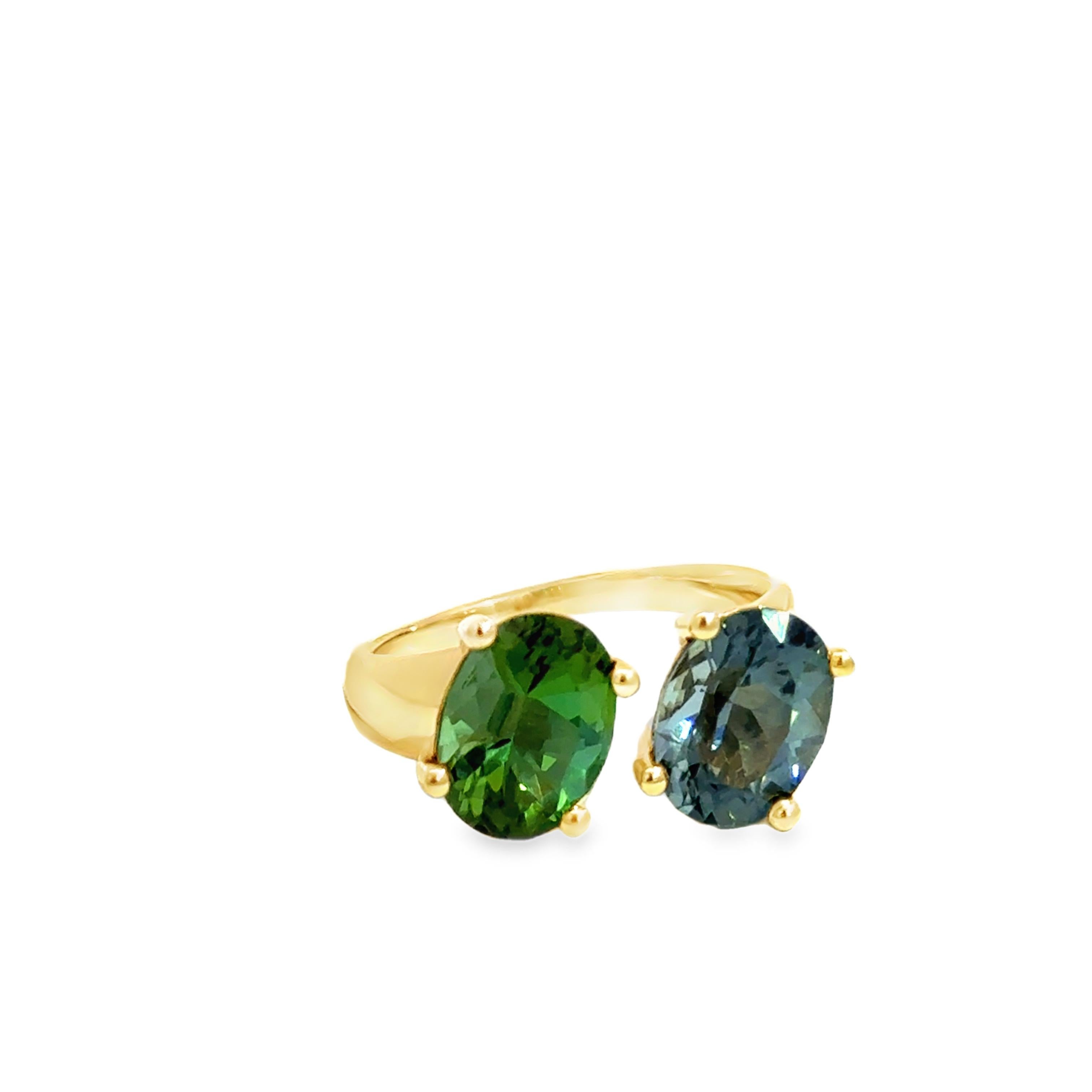 Cette exquise bague en or jaune 14k met en valeur une paire de tourmalines étonnante, composée d'une tourmaline verte vibrante (2,26 ct) et d'une tourmaline bleue profonde (2,26 ct) dans un design by-pass magnifiquement équilibré. L'élégante monture