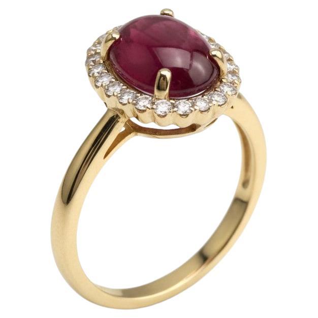 Réalisée en or jaune 14 carats, cette magnifique bague halo met en valeur un rubis cabochon d'un rouge profond pesant 2,96 carats. Lisse et brillant, le rubis attire l'attention au centre, entouré d'un halo de diamants ronds naturels d'une valeur
