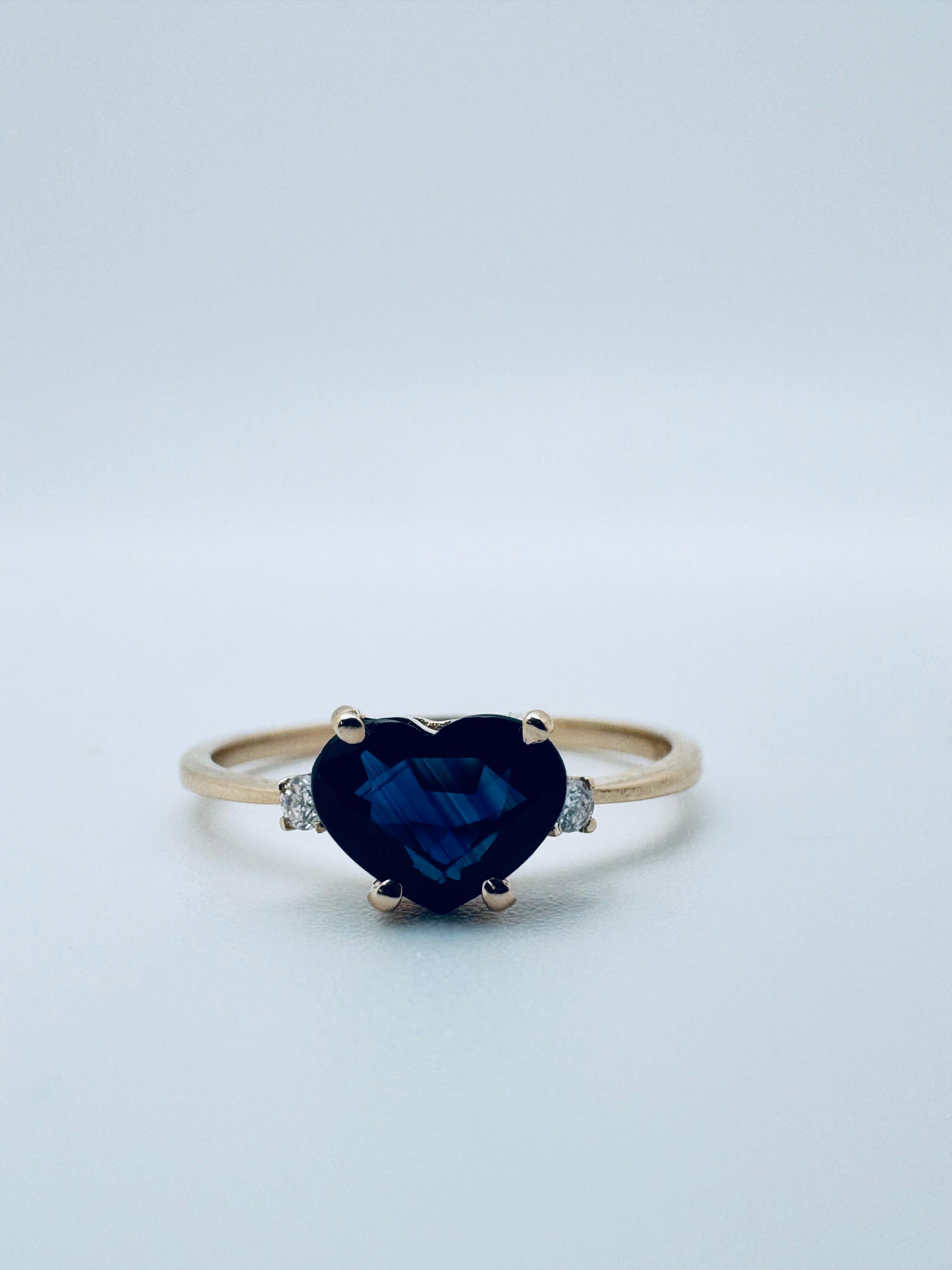 Cette bague en saphir bleu en forme de cœur offre un mélange intemporel d'élégance et de charme. Fabriquée en or jaune 14 carats poli, cette bague pèse 1,3 gramme, ce qui la rend à la fois légère et raffinée. En son centre se trouve un magnifique