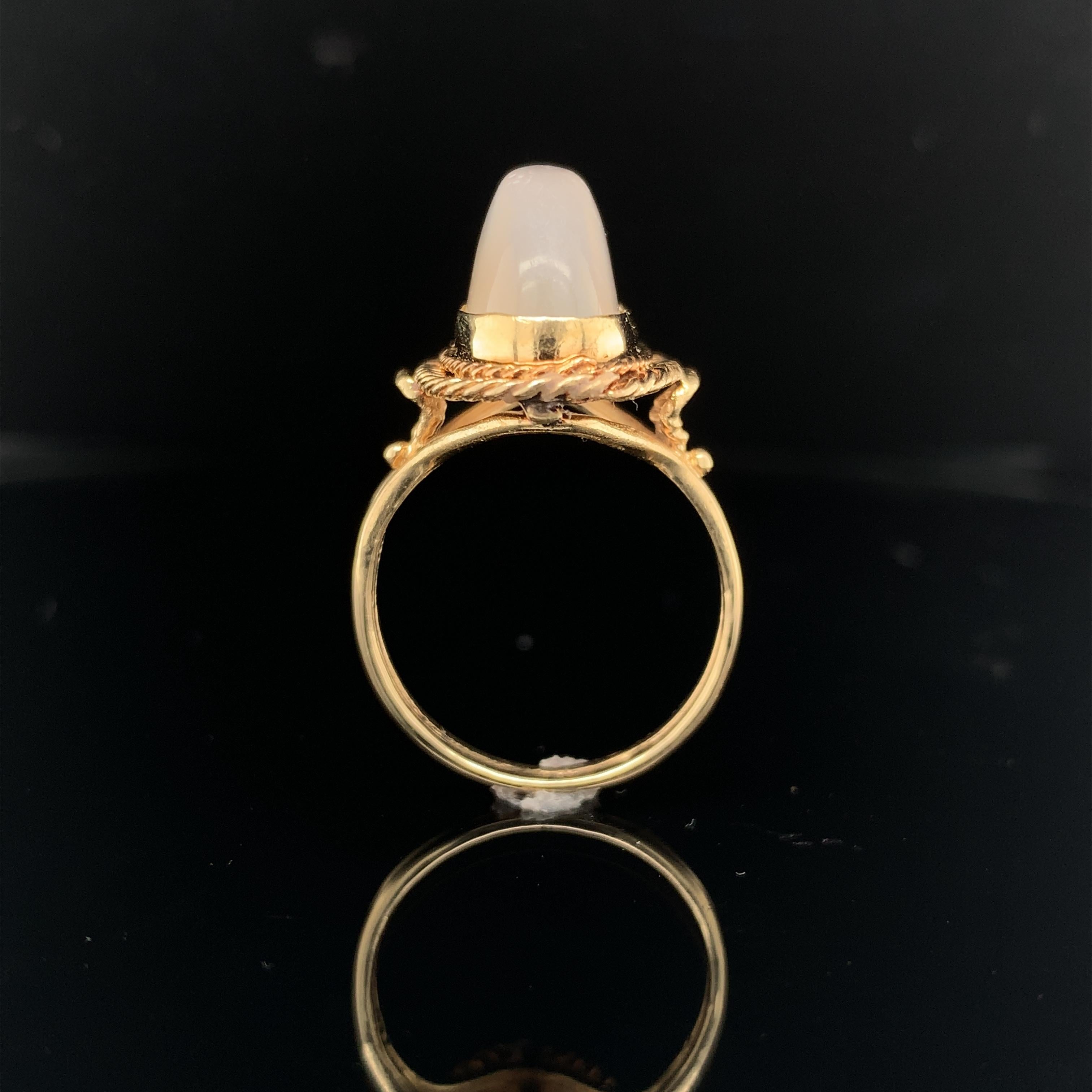 14k yellow gold ring featuring a large high dome oval moonstone.  The moonstone is a long oval bezel set in a hand wrought looped wire frame and wirework setting. The moonstone has white 