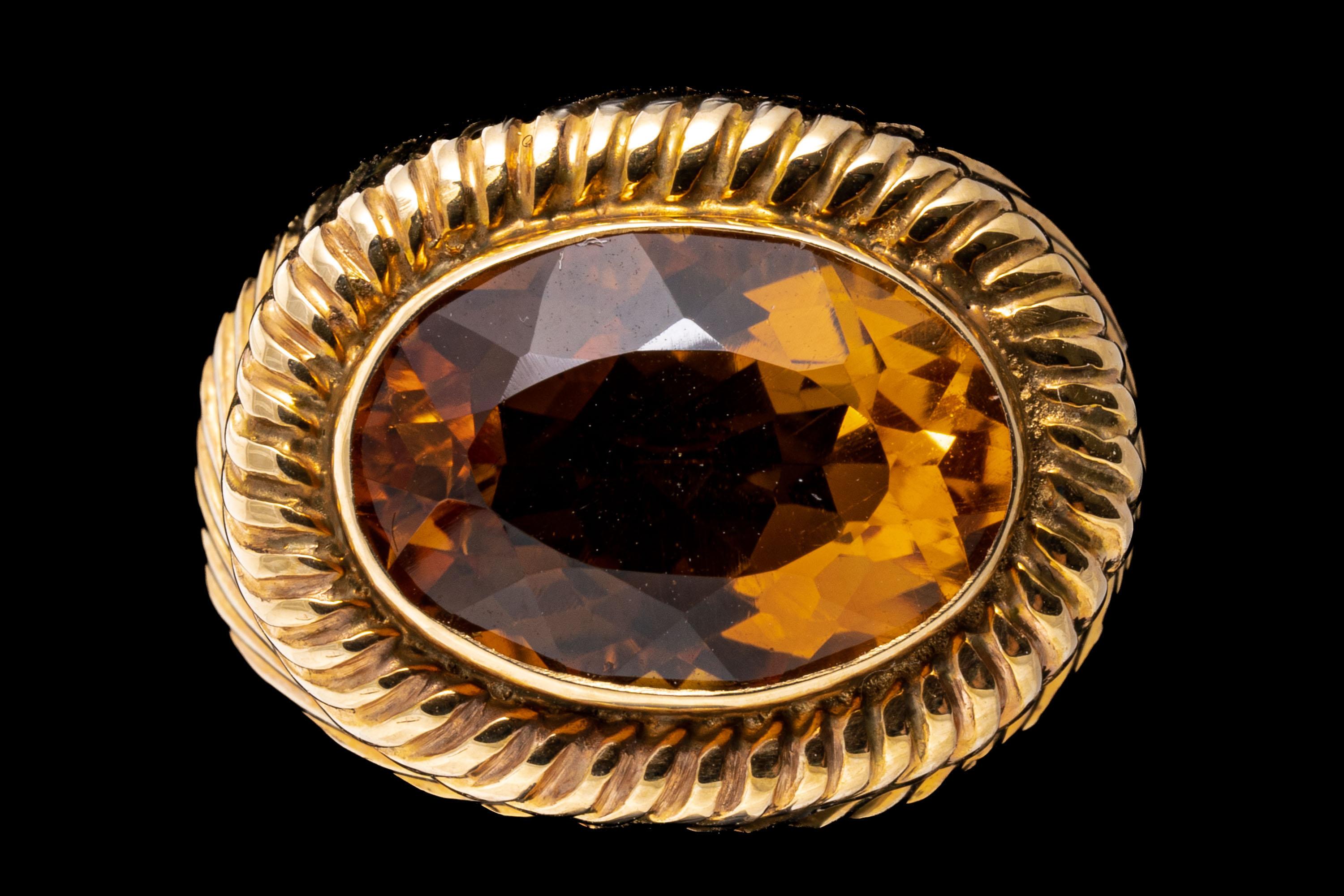 14k yellow gold ring. This simple, stunning ring features a horizontally situated, oval faceted, medium yellow orange color citrine, approximately 4.54 CTS, and bezel set into a twisted, finely ribbed dome style mounting.
Marks: 14k 
Dimensions: