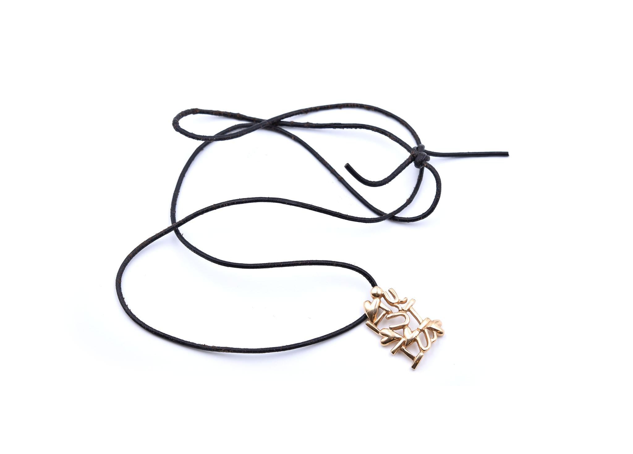 This pendant is crafted in 14k yellow gold and hangs from a black cord. The pendant depicts the text, “I Love U.”  It measures 33x23mm and weighs 17.20 grams. The black cord that the pendant hangs from measures approximately 32- inches in length and