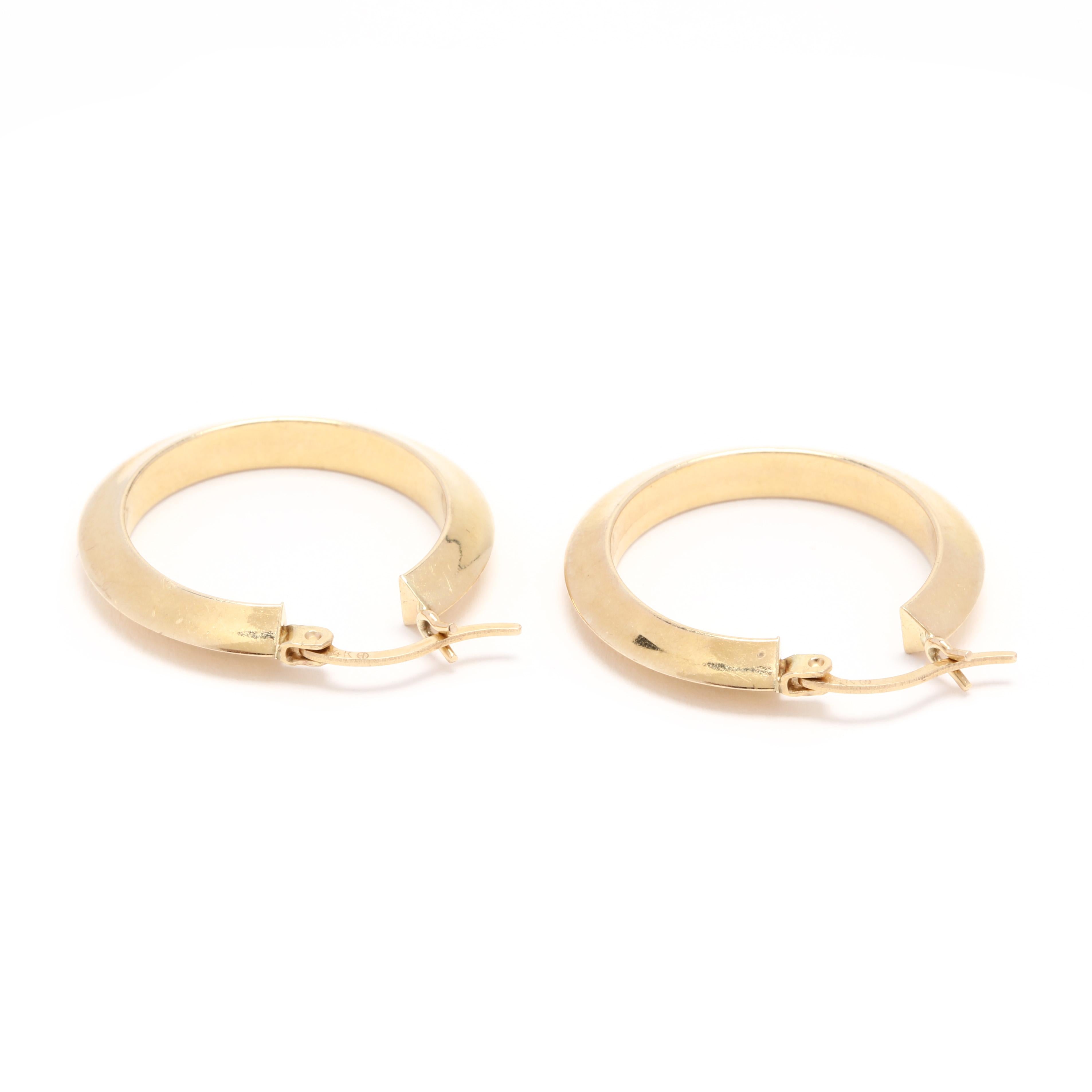 A pair of 14 karat yellow gold knife edge hoop earrings. These earrings feature a knife edge design in a circular design with a snap in closure.

Length: 1 in.

Width: 3.6 mm

2.27 dwts.

* Please note that this is a vintage item and may show signs