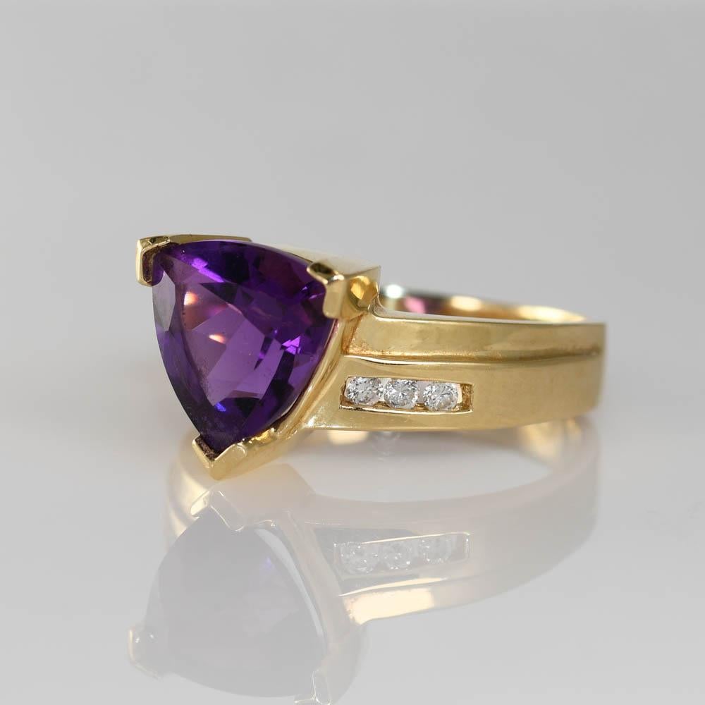 14k Yellow Gold amethyst and diamond ring.
The center stone is a Triangular cut Amethyst set with six .01ct Round Diamonds. 
Amethyst measures 9.8mm w 10.8mm L
weighs 5.7g, stamped 14k
size 9
Like new