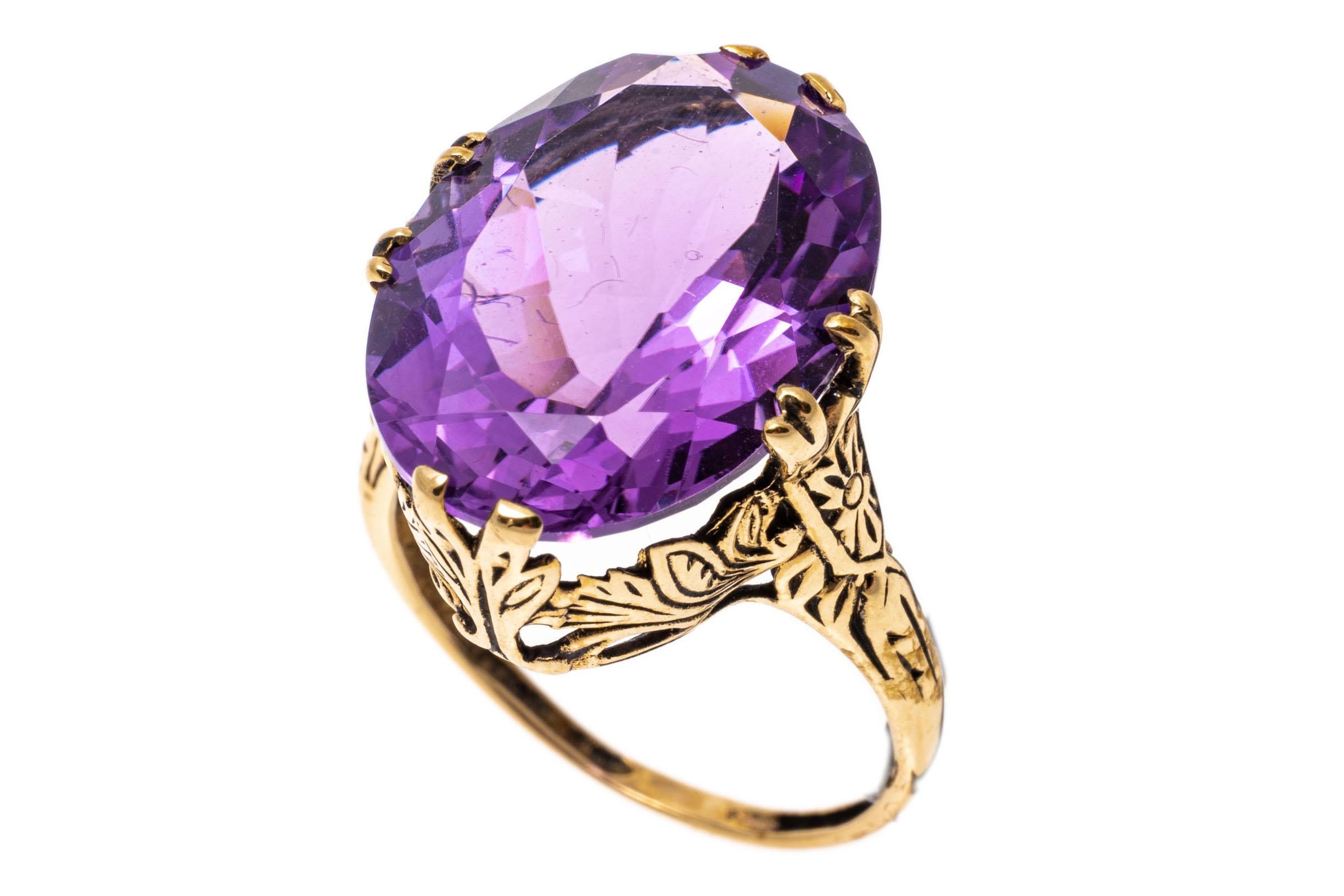 14k yellow gold ring. This beautiful, vintage ring has a large center oval faceted, medium to light purple color amethyst, approximately 10.94 CTS and set with foliate decorated split prongs, which lead into a lovely foliate gallery and patterned