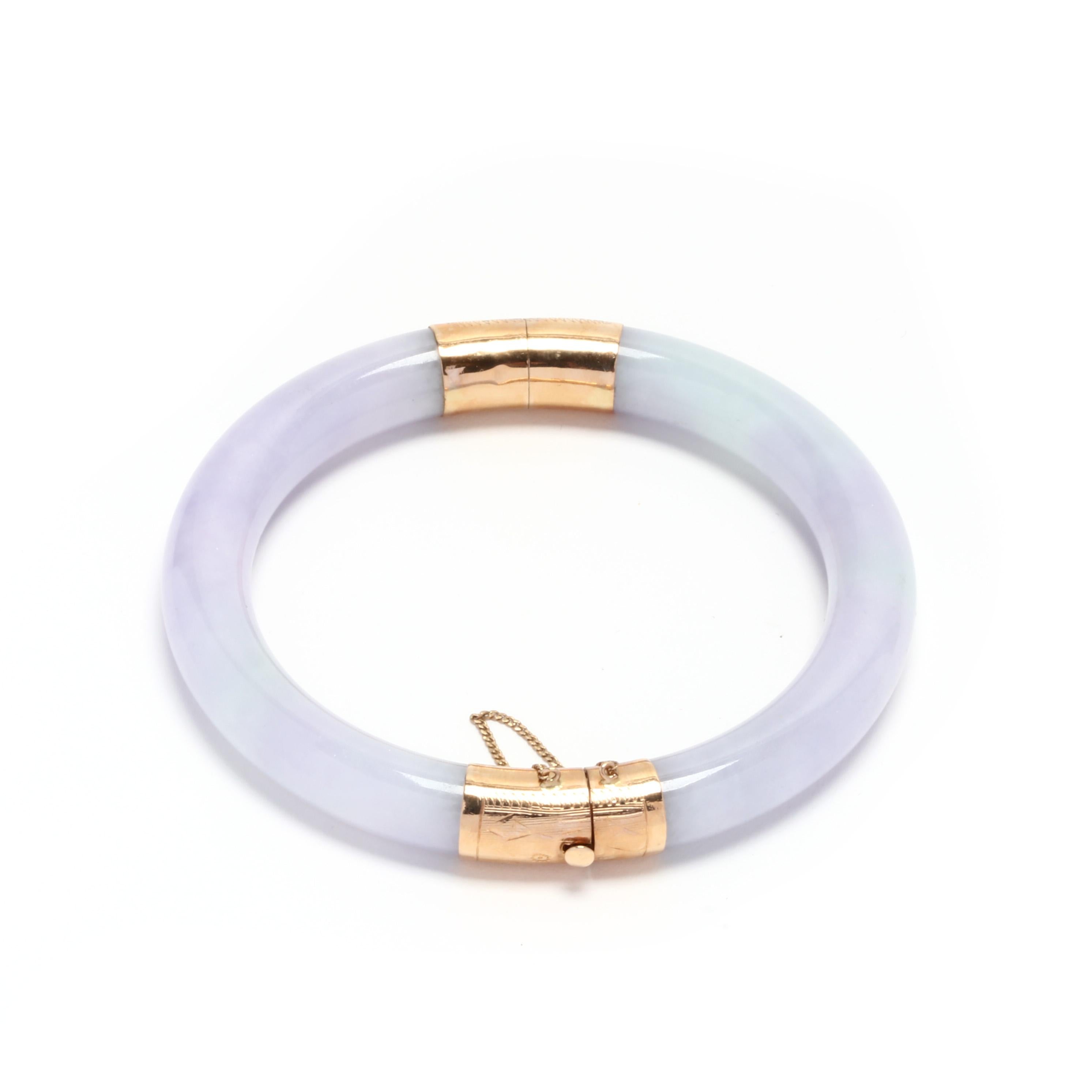 A 14 karat yellow gold lavender jade hinged bangle bracelet. This carved lavender jade bangle has floral engraved gold end caps with a hinge at one end and a clasp at the other.

Length: 7 1/8 in.

Width: 9.25 mm

29.78 dwts.

* Please note that