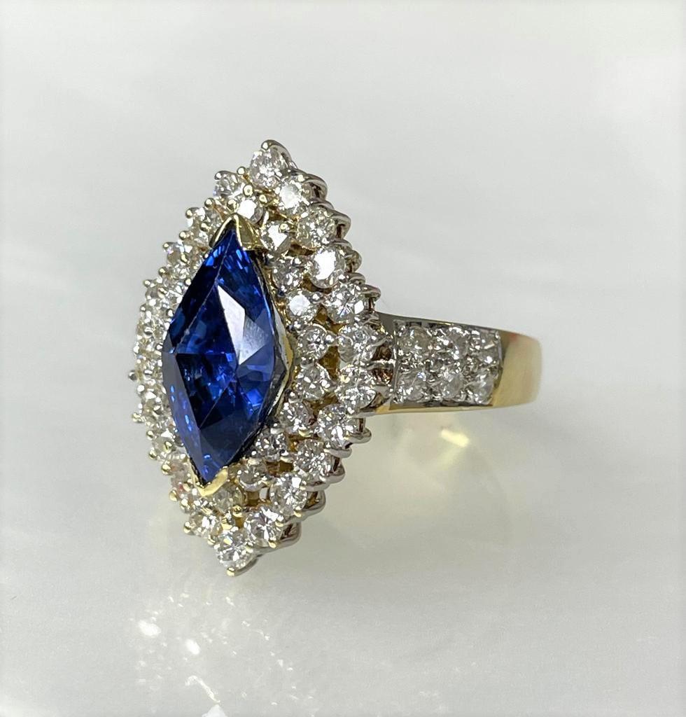 A rare and luxurious vintage blue sapphire ring featuring a vibrant marquise shaped center stone weighing 4.32 carats surrounded by 1.47 carats of sparkling white diamonds set in solid 14k yellow gold.

*Approximate stone measurements:
Height: