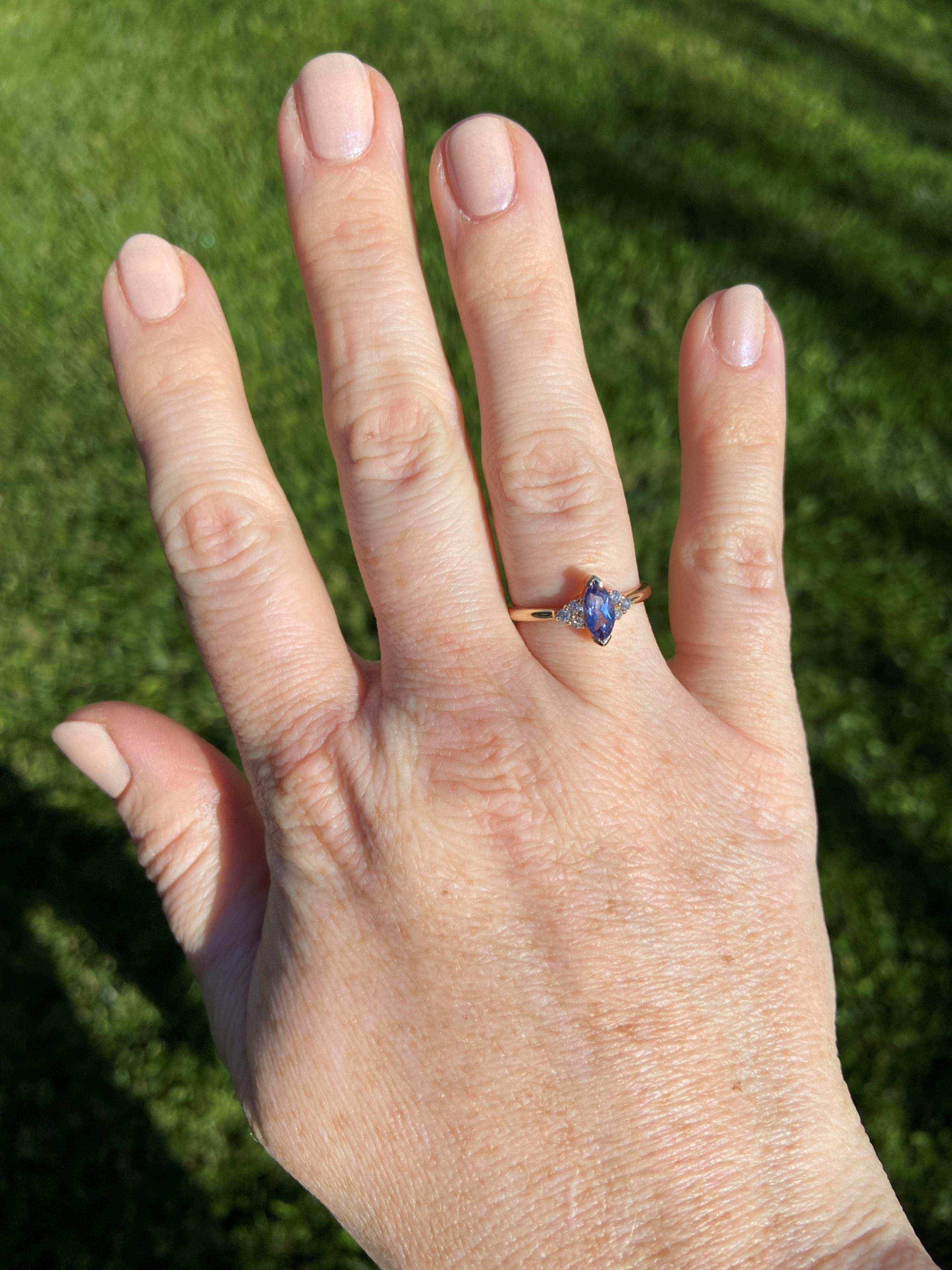 Set in 14k yellow gold, this .58ct marquise-cut tanzanite shows off its periwinkle blue color. On either side of the tanzanite is a trio of round H-I color, SI1-SI2 clarity diamonds, which add a total of .12tcw of sparkle to this ring. 
Tanzanite