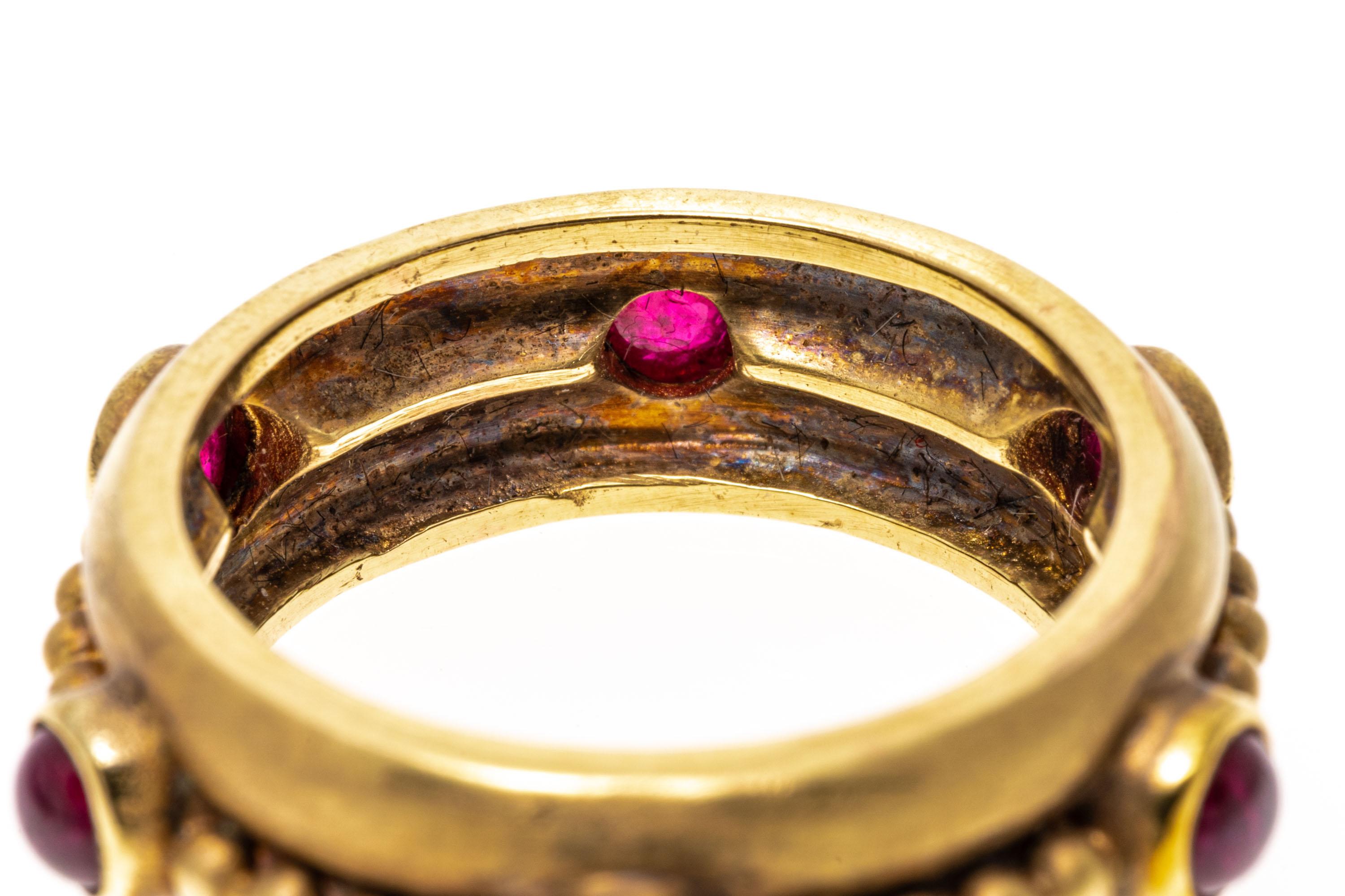 14k yellow gold ring. This striking ring is a matte finished, wide eternity band, with six round red color synthetic ruby cabachons, bezel set and finished by a horizontal bead running through the center.
Marks: None, tests 14k
Dimensions: 9/32