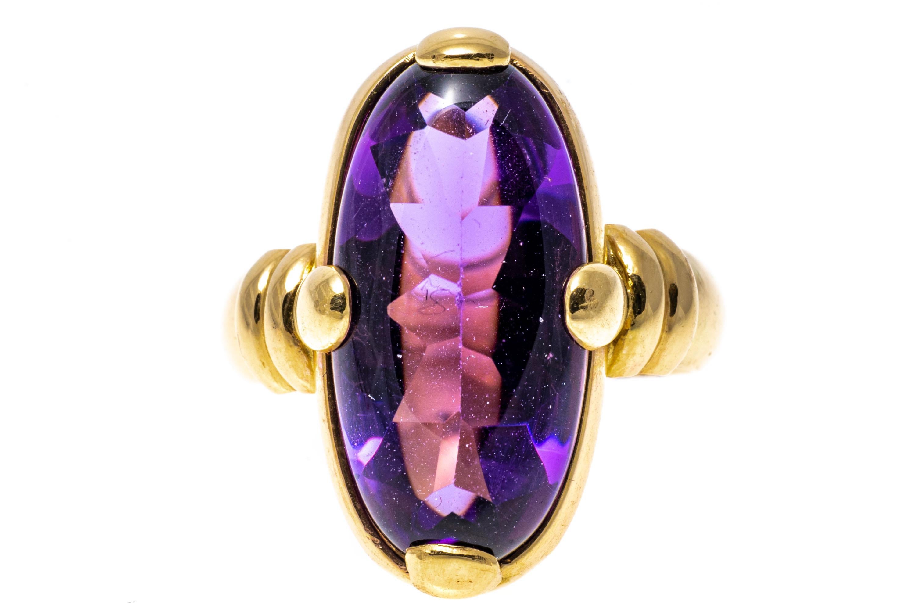 14k yellow gold ring. This pretty, uncommon ring has an elongated oval, half-faceted and half cabochon cut, dark purple color amethyst, set with wide prongs and finished with ribbed shoulders and a wide shank.
Marks: 14k
Dimensions: 3/8