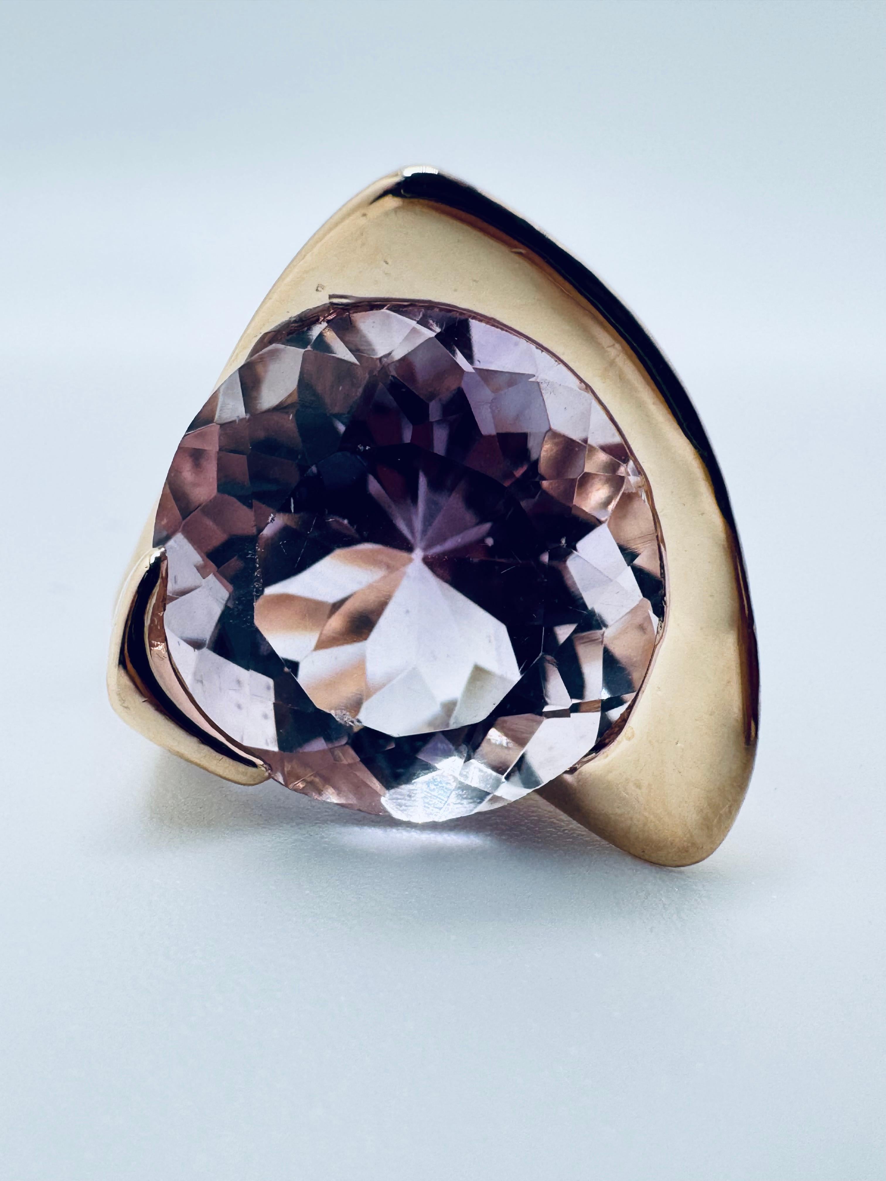 Cette élégante bague en or jaune 14 carats met en valeur une superbe morganite ronde de 15,0 mm de diamètre dans une magnifique teinte rose moyen. La pierre précieuse est facettée et sertie dans un demi-bélier distinctif, permettant à la lumière de