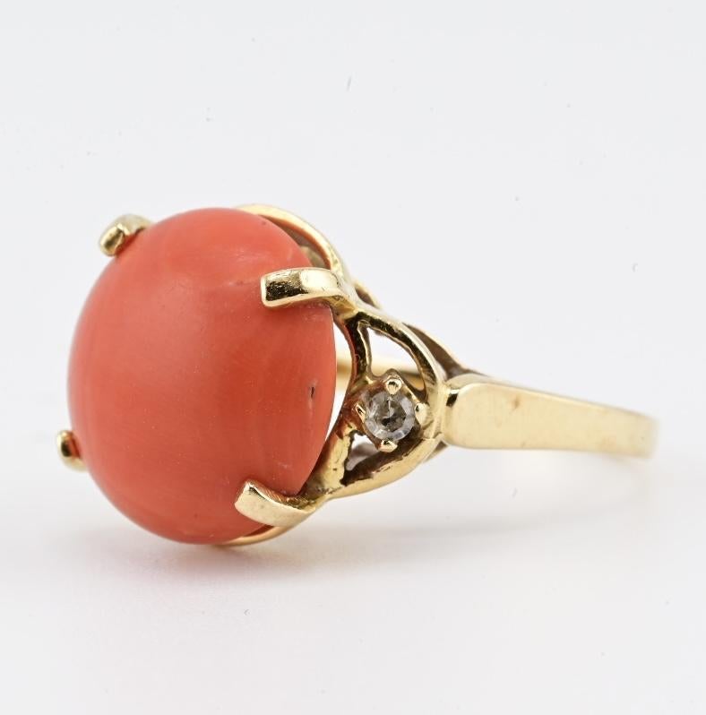Dieser elegante Ring aus 14-karätigem Gelbgold zeigt einen kühnen und wunderschön erhaltenen natürlichen Korallencabochon mit einer Größe von etwa 14,17 × 14,08 mm. Die Koralle weist einen warmen, satten Lachston mit glatter Politur und