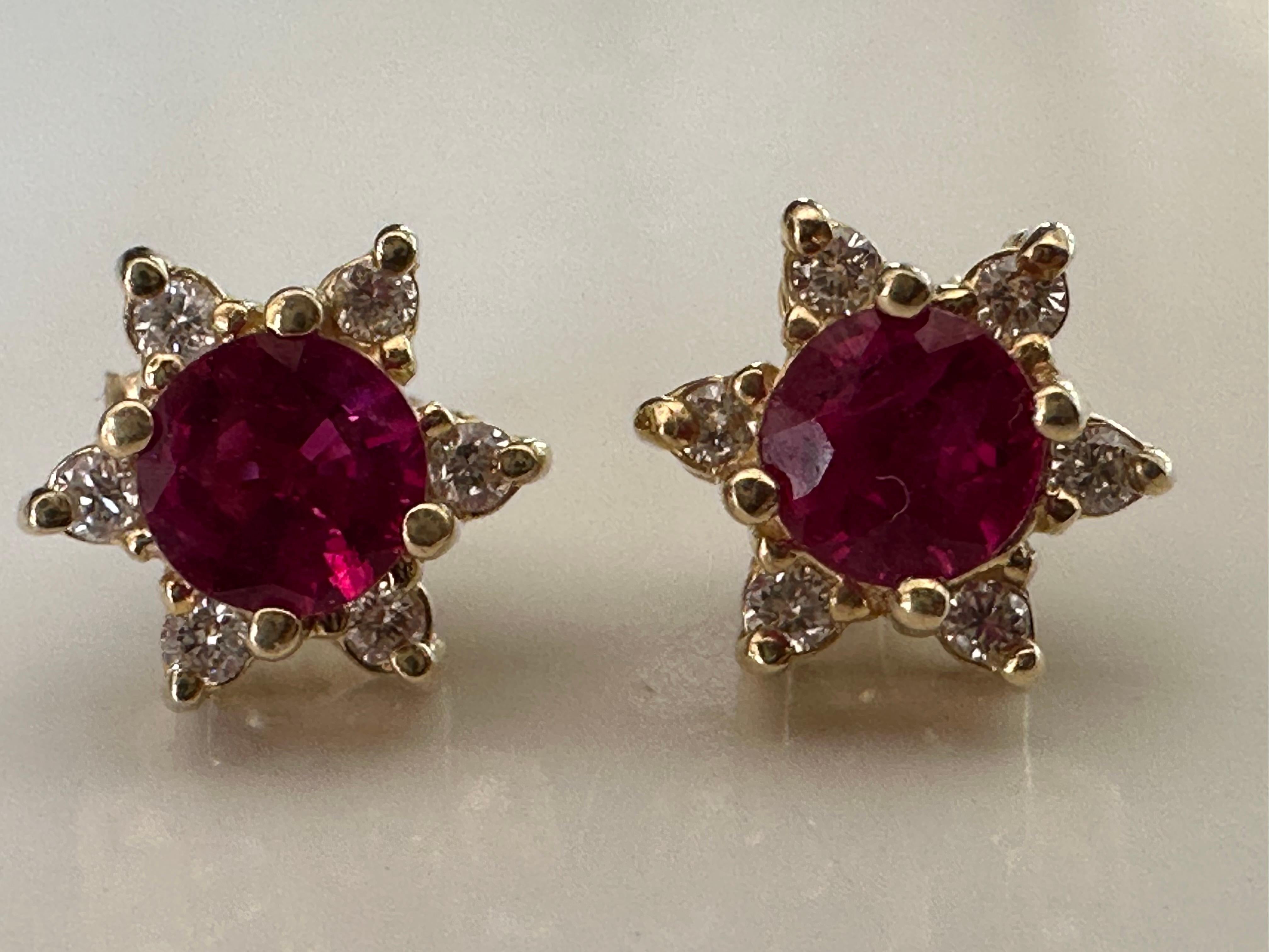 Crafted in 14K yellow gold, these earrings feature two natural round rubies each measuring 4.4mm, complemented by twelve glittering round brilliant-cut diamonds totaling approximately 0.12 carats set in a pretty floral design. 

