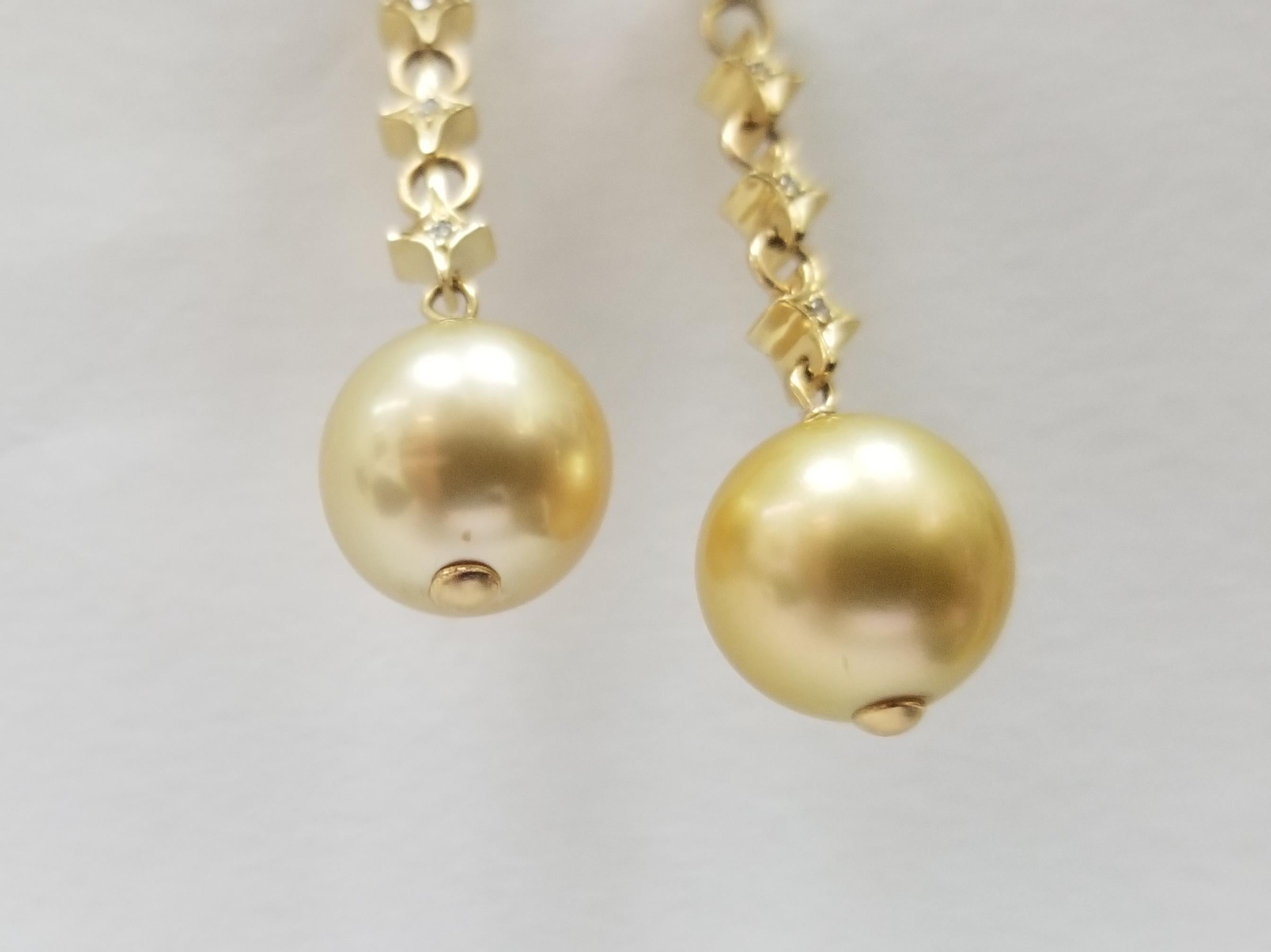 14k yellow gold Natural white and yellow South Sea pearl and diamond earrings, containing 2- 8.5 mm natural white south sea pearls and 2- 12mm natural yellow south sea pearls.  set with 6 round full cut diamonds weighing .06pts.
