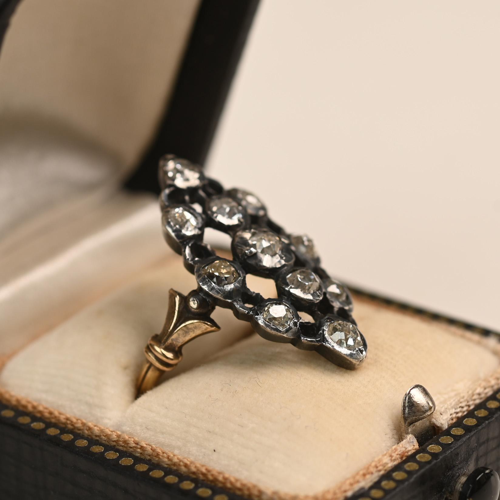 Un cautivador anillo de la Era Georgiana que muestra una elegante silueta navette adornada con un intrincado trabajo de filigrana de diamantes. Los hombros están adornados con un refinado motivo de flor de lis, que añade un toque de encanto regio.