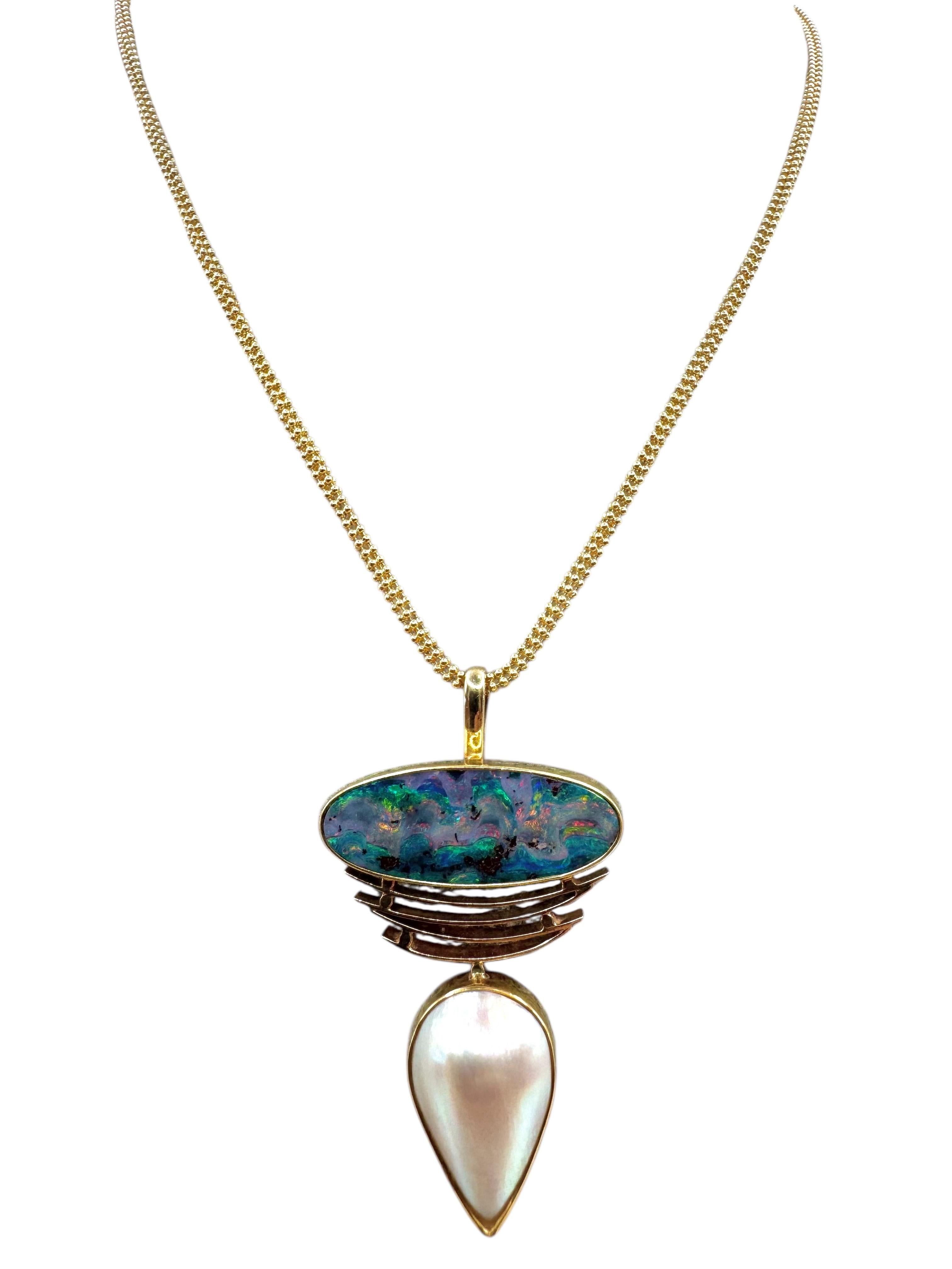 Una straordinaria collana di manifattura italiana realizzata in oro giallo 14 carati, con un vibrante opale ovale cabochon incastonato sopra un'elegante perla mabe a forma di pera. L'opale mostra un accattivante gioco di colori nelle tonalità del