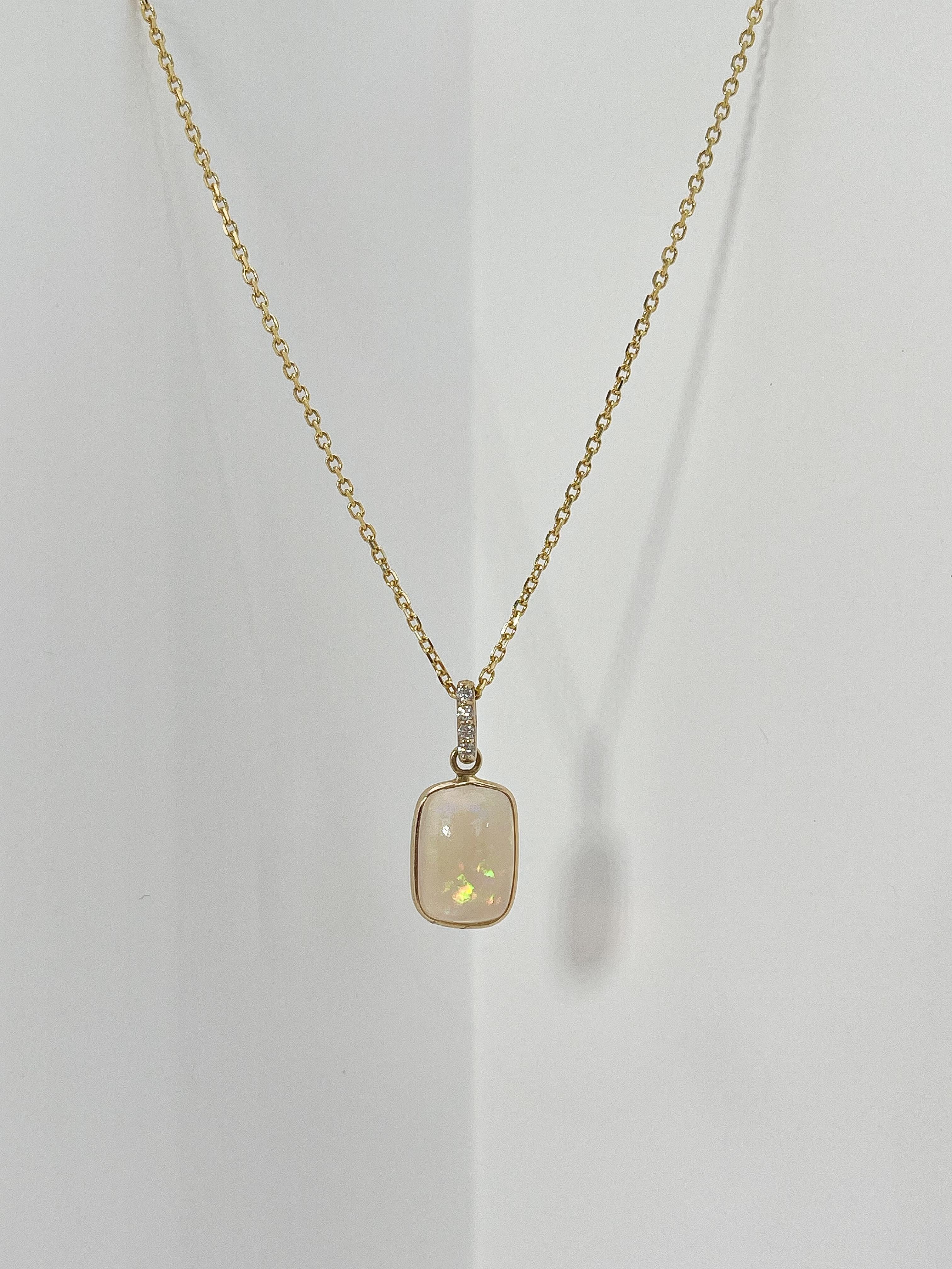 14k yellow gold opal and .06 CTW diamond pendant necklace. The diamonds in the bail are all round, the measurements of the pendant are 12.5 x 9, and the length of the necklace is 16 inches, and it has a total weight of 3.13 grams.