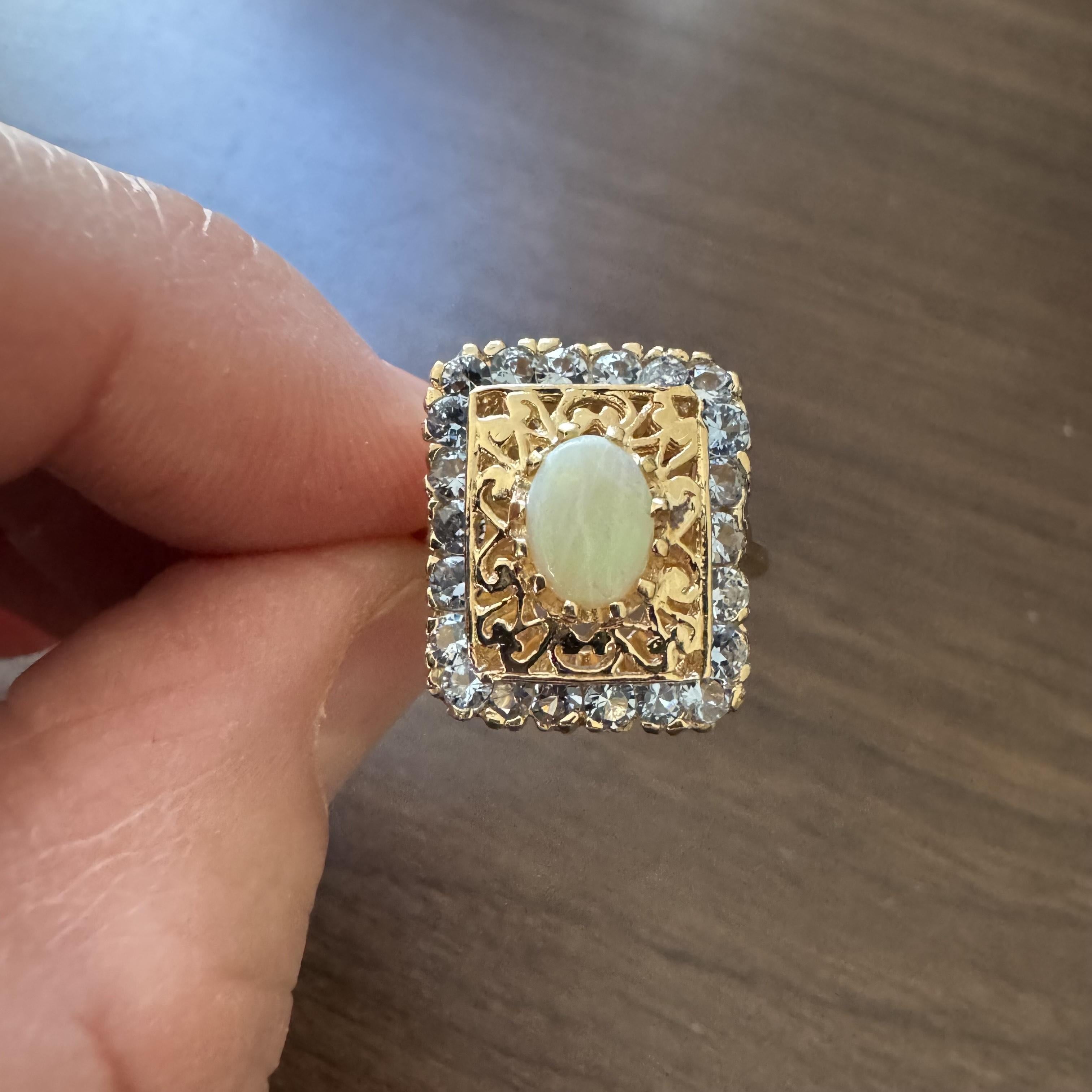 Condition:  Excellent Condition, Professionally Cleaned and Polished
Metal:  14k Gold (Marked, and Professionally Tested)
Weight:  8.9g
Gemstone: Oval Cut Opal 8mm by 5.5mm  
Gemstone:  Round Cut Aquamarines
Face Measurement:  19mm by 16mm
Band