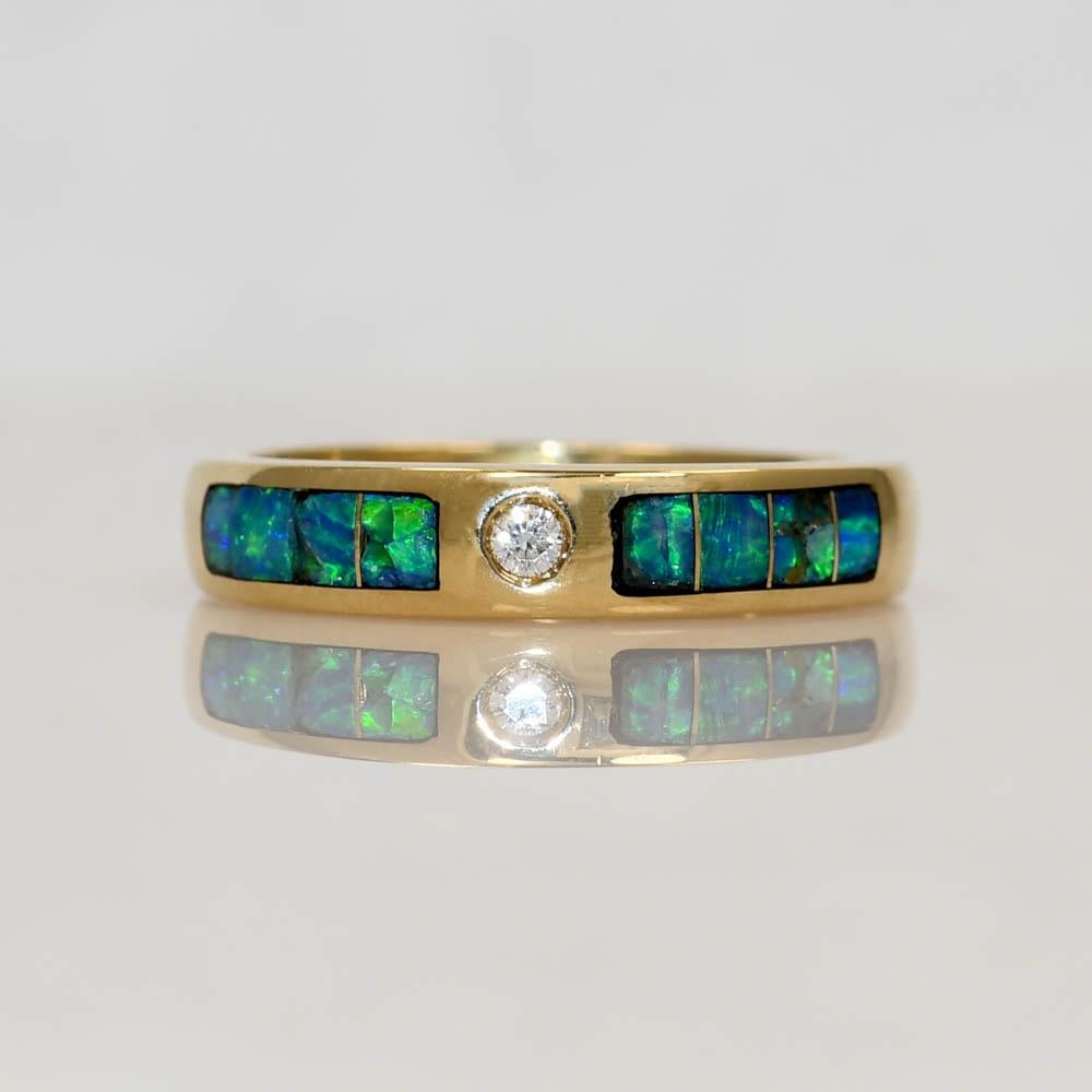 Australian black opal and diamond band in 14k yellow gold.
Stamped 14k and weighs 4.9 grams.
The opals are inlaid.
Some chips are visible in the opals.
The diamond is a round brilliant cut, .04 carat, G color, VS clarity.
The ring measures 4.3mm
