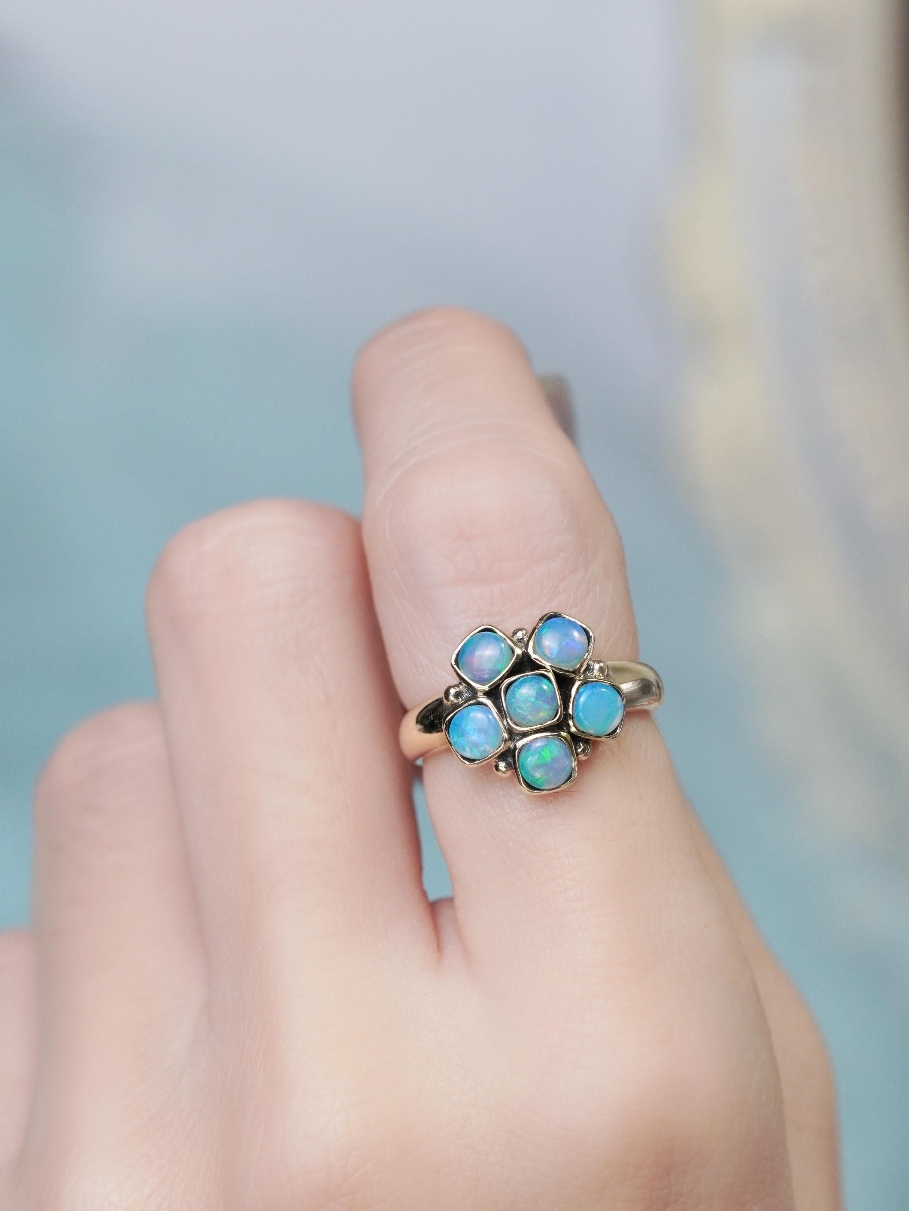 A luminous round opal cluster takes center stage in this vintage-style ring, blossoming like a tiny, radiant flower. Soft flashes of color ripple across its surface, capturing the gentle magic of a garden in bloom. Delicate antique-inspired