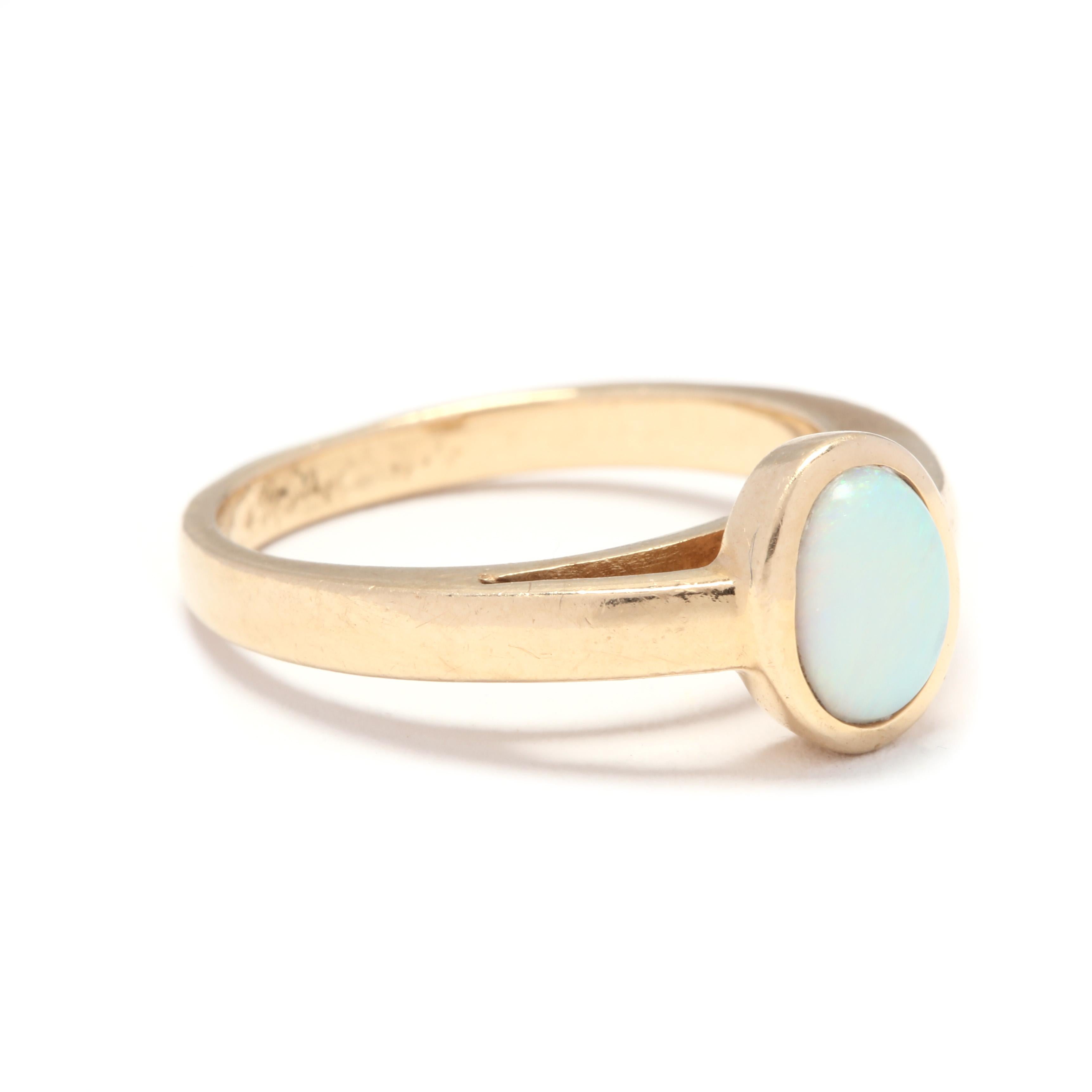 A 14 karat yellow gold and opal solitaire bezel ring. This ring features an oval cabochon opal that is bezel set and suspended above a polished band.

Stones:
- opal
- oval cabochon, 1 stone
- 7 x 5.15 mm

Ring Size 6.25

2.84 dwts.

* Please note