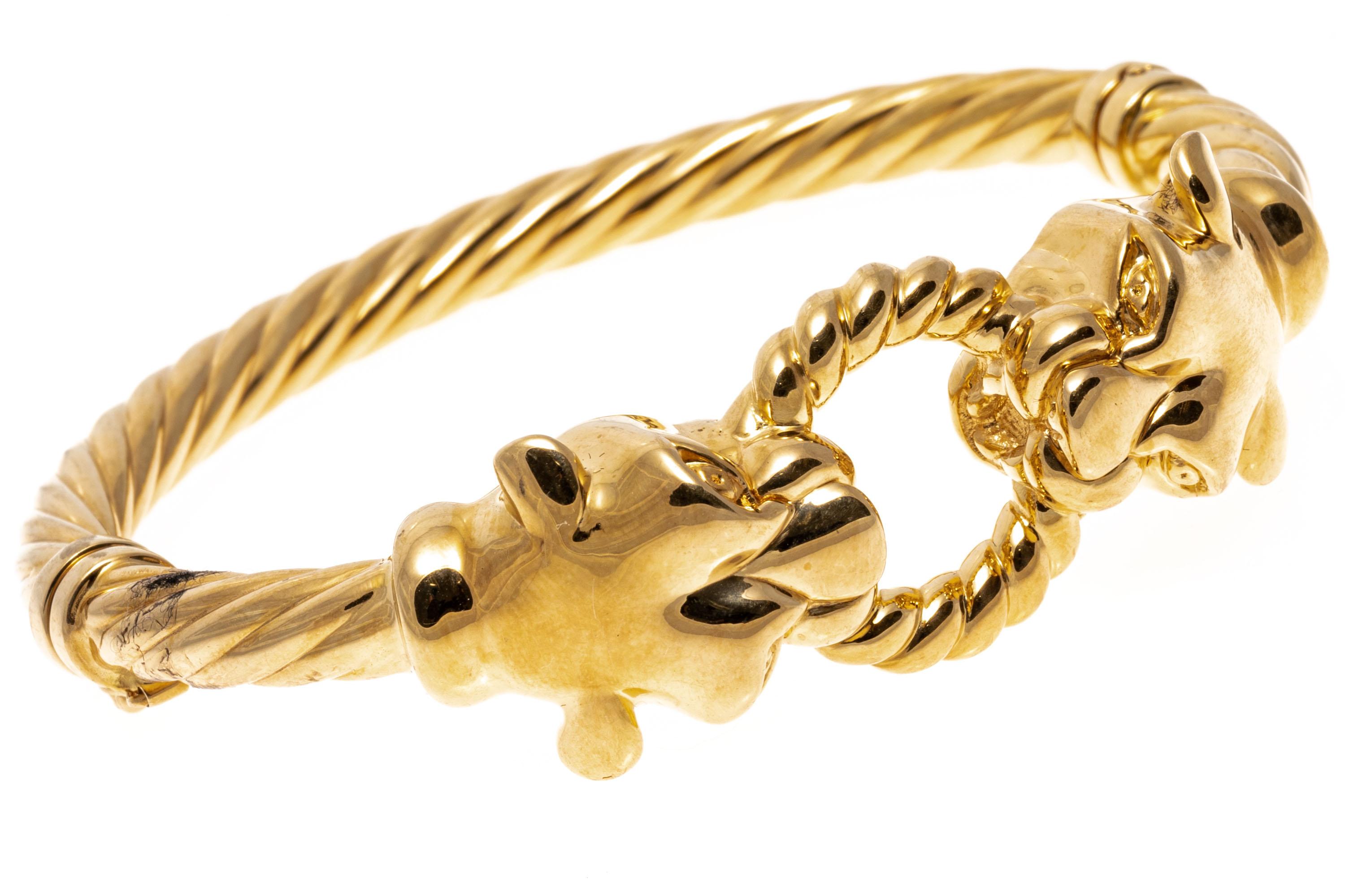 Bracelet en or jaune 14k. Ce bracelet percutant est un bracelet à charnière, de style torsadé, avec un motif central opposant deux panthères tenant un anneau torsadé dans leur gueule. Le bracelet est doté d'un fermoir en forme de huit.
Marques :