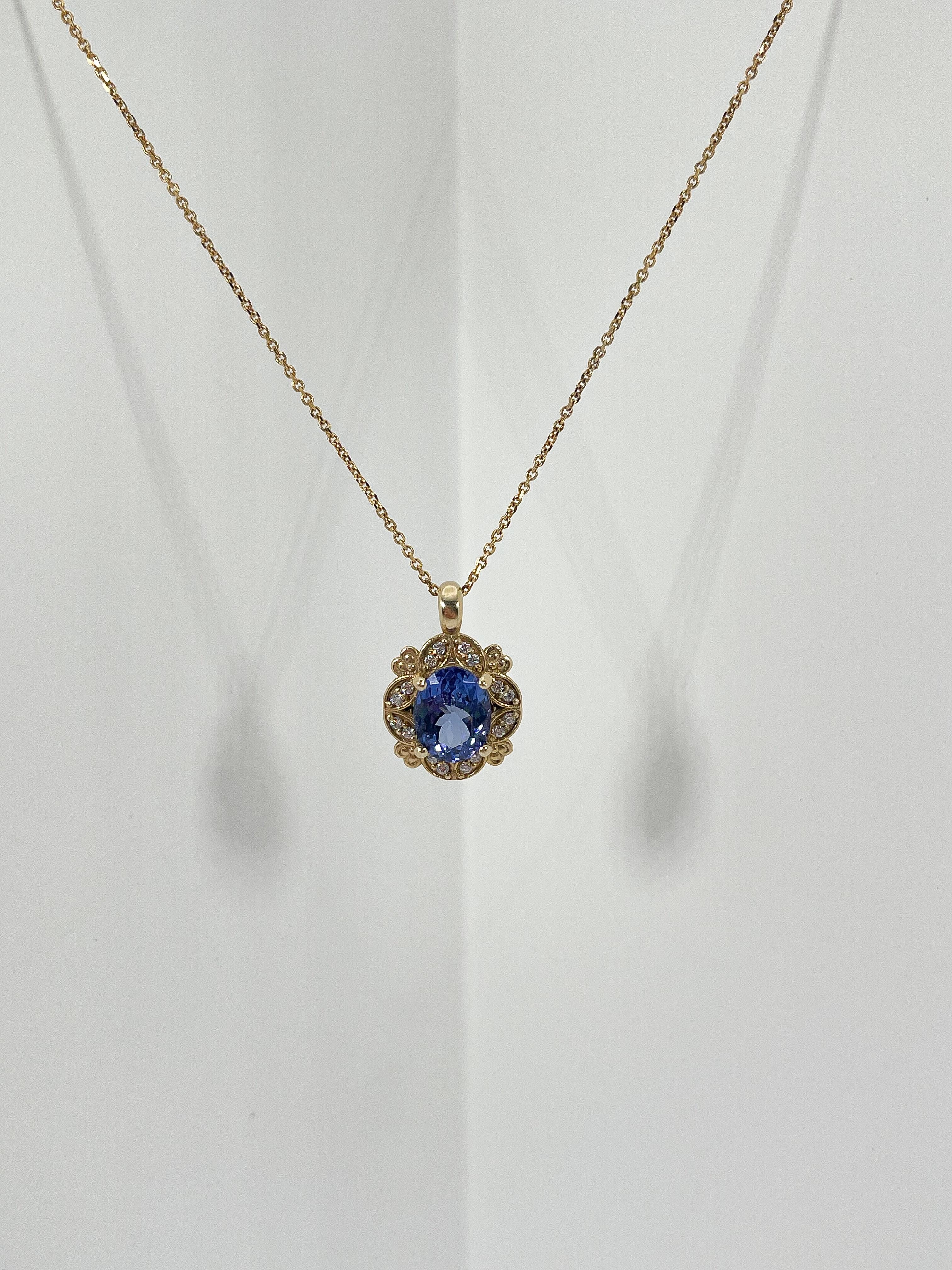 14K yellow gold pendant necklace with oval 2.20 carat Tanzanite and round diamonds on the outside. The size of the pendant measures 14.5 x 13.5mm, and the stone measures 9.4 x 7.4mm. The weight of the necklace is 5.7 grams and measures 18 inches.