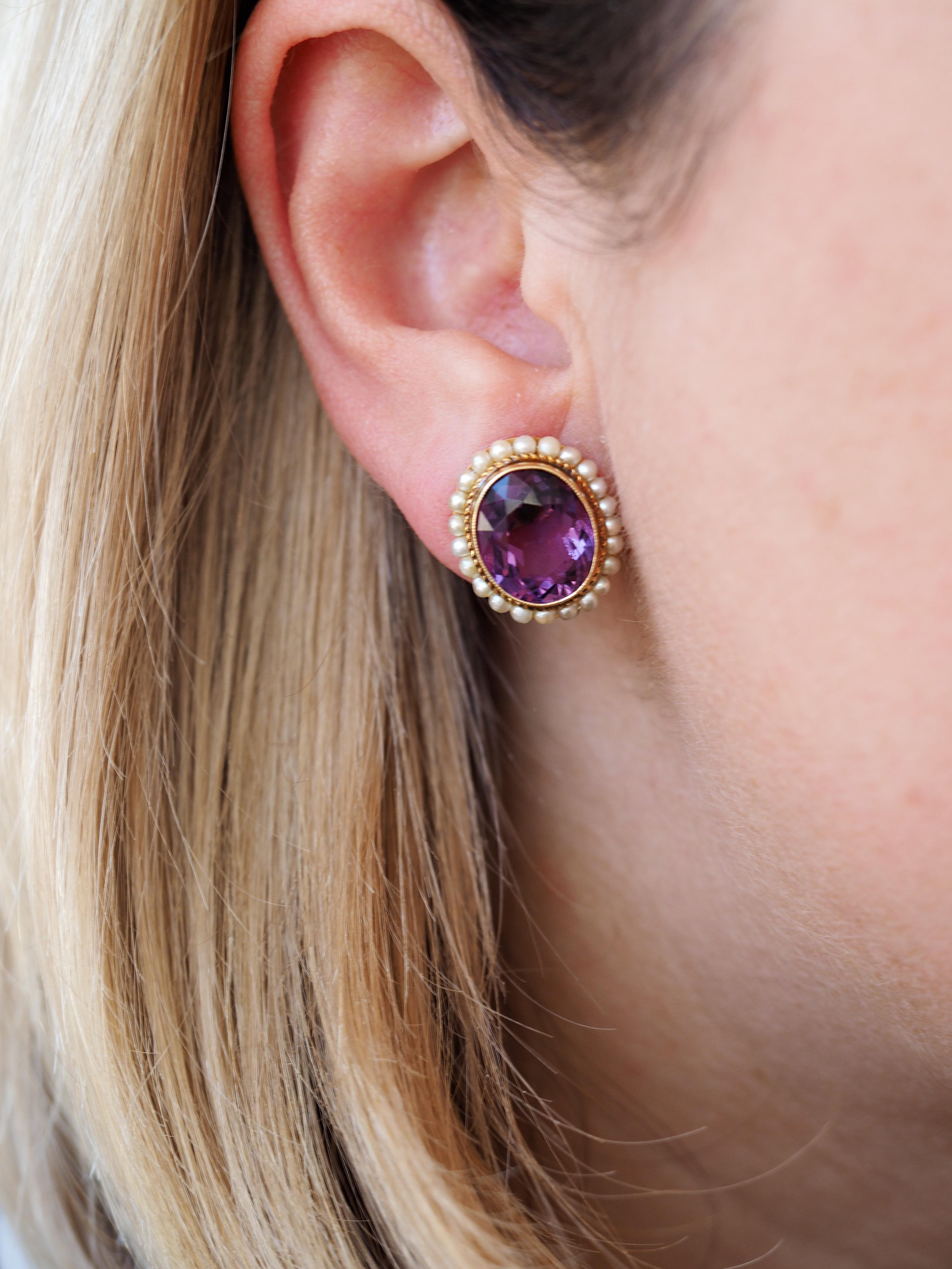14 Karat Yellow Gold Victorian Style Oval Amethyst Earrings Bezel Set and Framed by Seed Pearls  The earrings feature a matched pair of faceted oval amethyst measuring 11.68 x 9.78 x 6.61 mm and 11.79 x 9.90 x 6.68 mm and weighing approximately 8.13