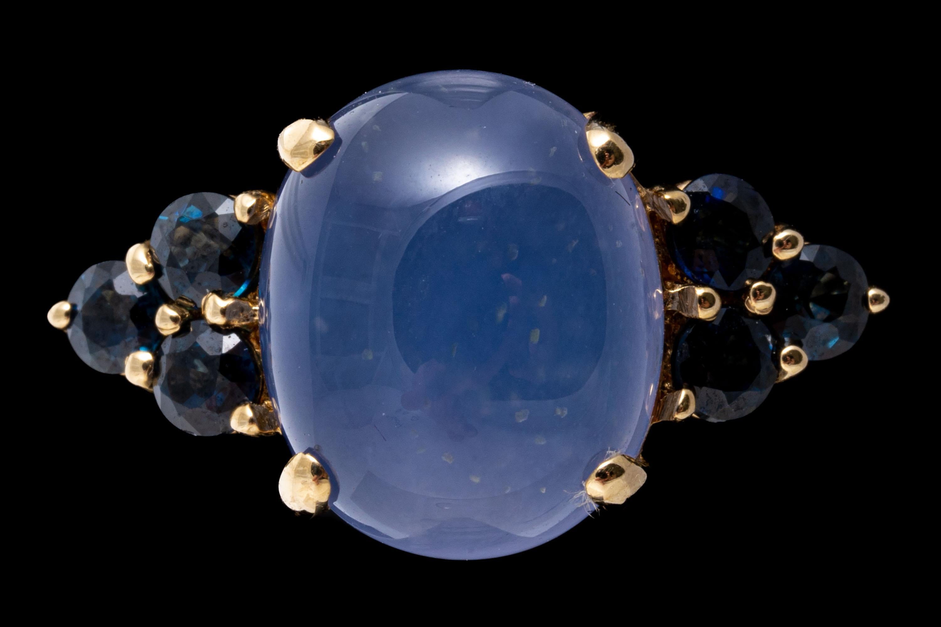 14k yellow gold ring. This colorful ring has an oval cabachon, blue chalcedony center, prong set and flanked by three round faceted, dark blue color sapphires, approximately 0.72 TCW and also prong set. 
Marks: 14k
Dimensions: 13/16
