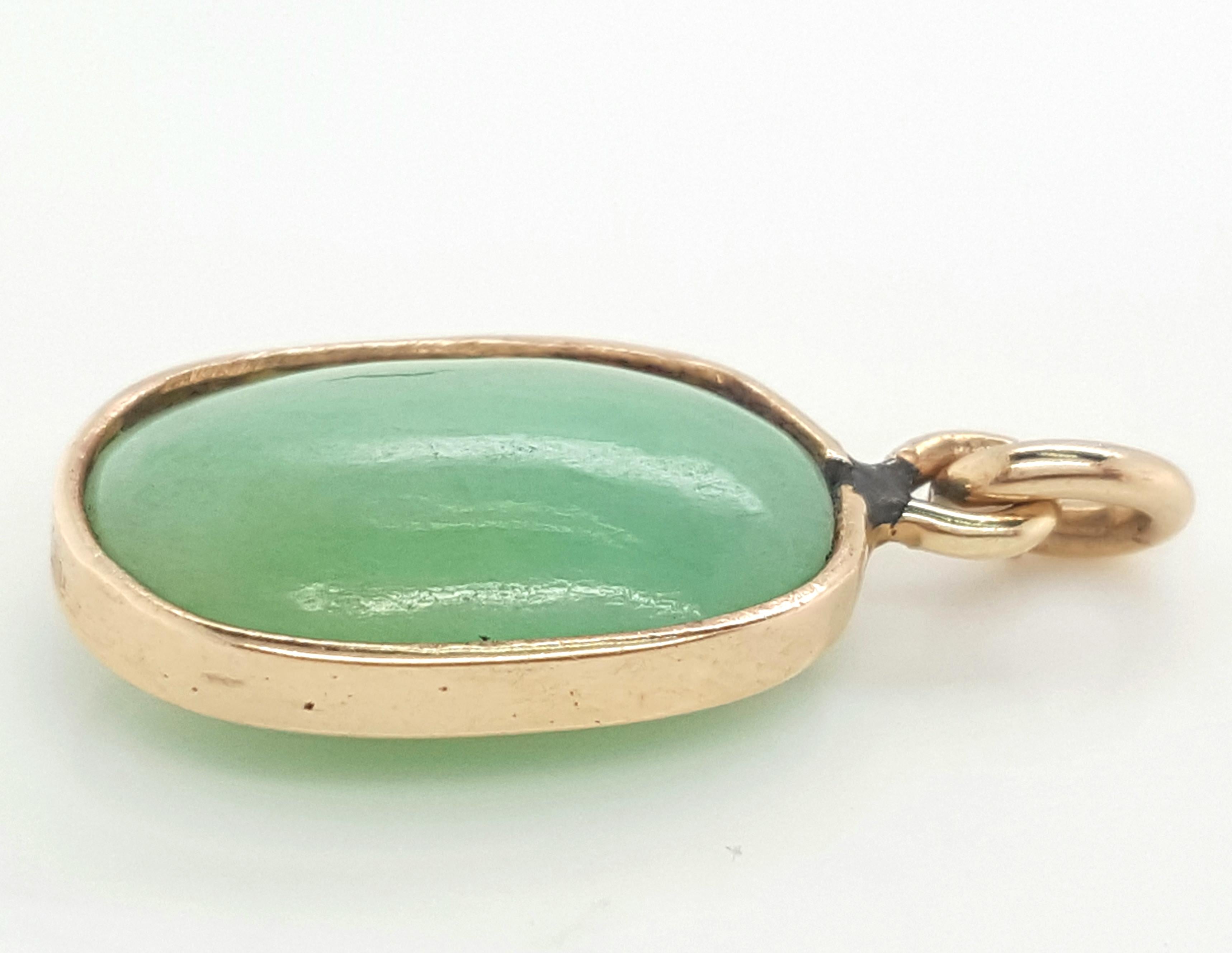  Ciondolo a castone aperto in oro giallo 14 carati con doppio cabochon ovale di giadeite.  La giada è un doppio cabochon ovale di 15,59 cm.  x 10,42 x 5,77 mm.  La pietra è trattenuta da un castone stretto in oro giallo 14 carati, completato da un