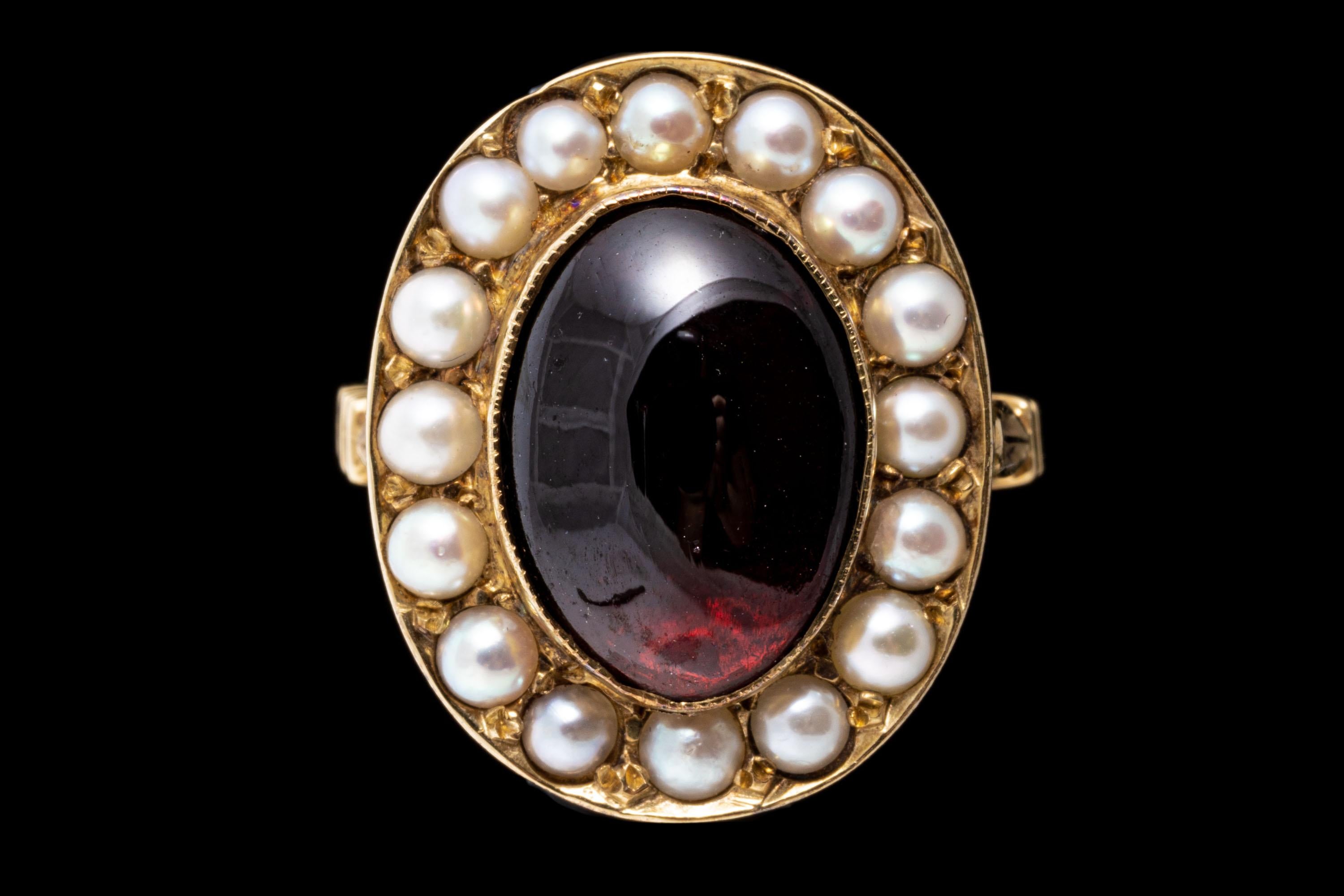 Ring aus 14k Gelbgold. Dieser Vintage-Ring aus Gelbgold hat einen länglichen ovalen Cabachon-Granat in dunkler Burgunderfarbe in der Mitte, der mit einem Halo aus weißen Zuchtsteinen von 2,5 mm Durchmesser in Zackenfassung verziert ist. Der Ring ist