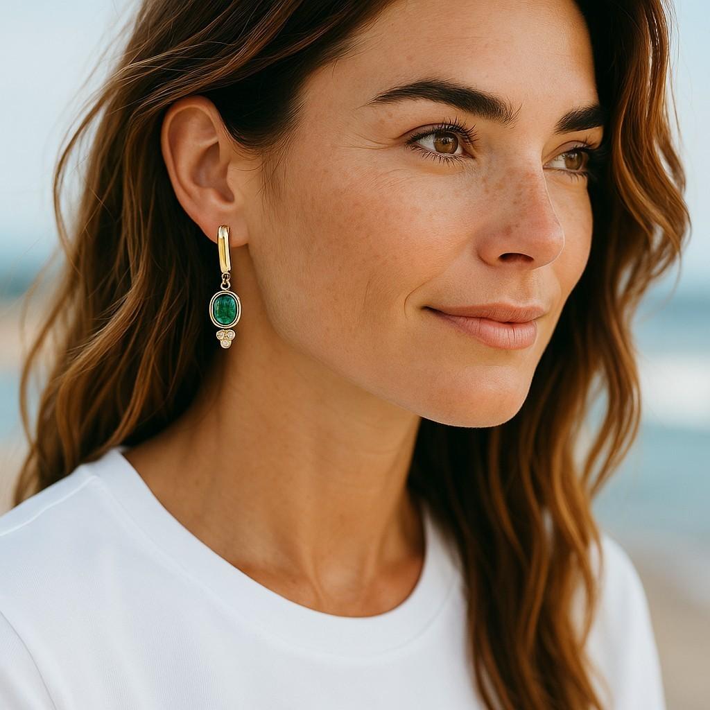 Célébrez l'élégance intemporelle et la couleur vibrante avec ces boucles d'oreilles pendantes en or jaune 14 carats, mettant en vedette deux émeraudes lumineuses de forme ovale totalisant 1,40 carat. Accentuées par 0,15 carats de diamants ronds